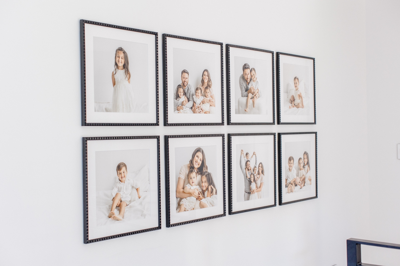 Gallery wall with eight custom, square black wood frames. Design and installation provided by full service family photographer, Sana Ahmed Photography.