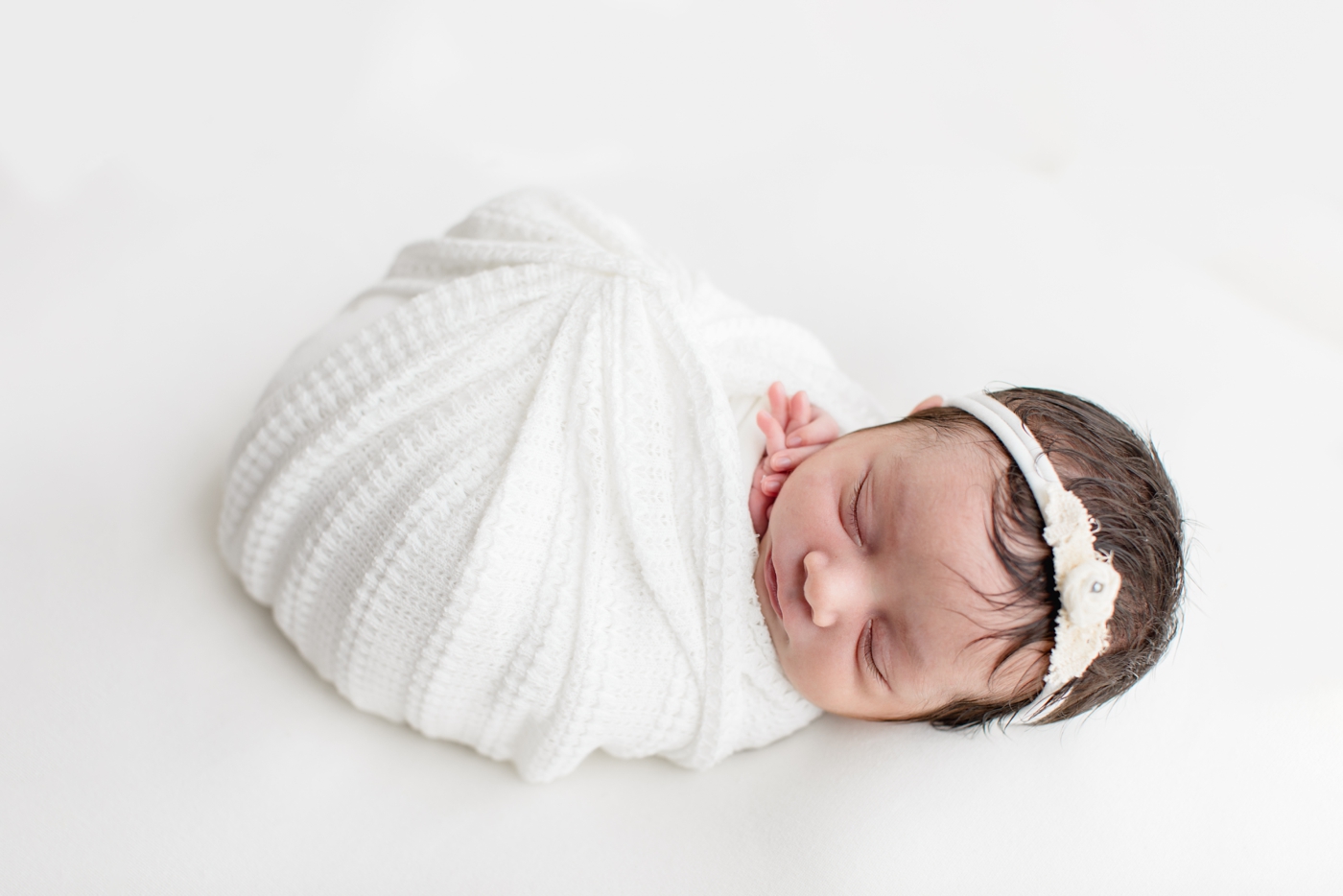 Baby girl in white swaddle. Photo by Austin Newborn Photogrpaher, Sana Ahmed Photography.