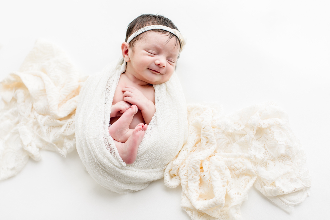 Baby smiling in white swaddle. Photo by Austin Newborn Photographer, Sana Ahmed Photography