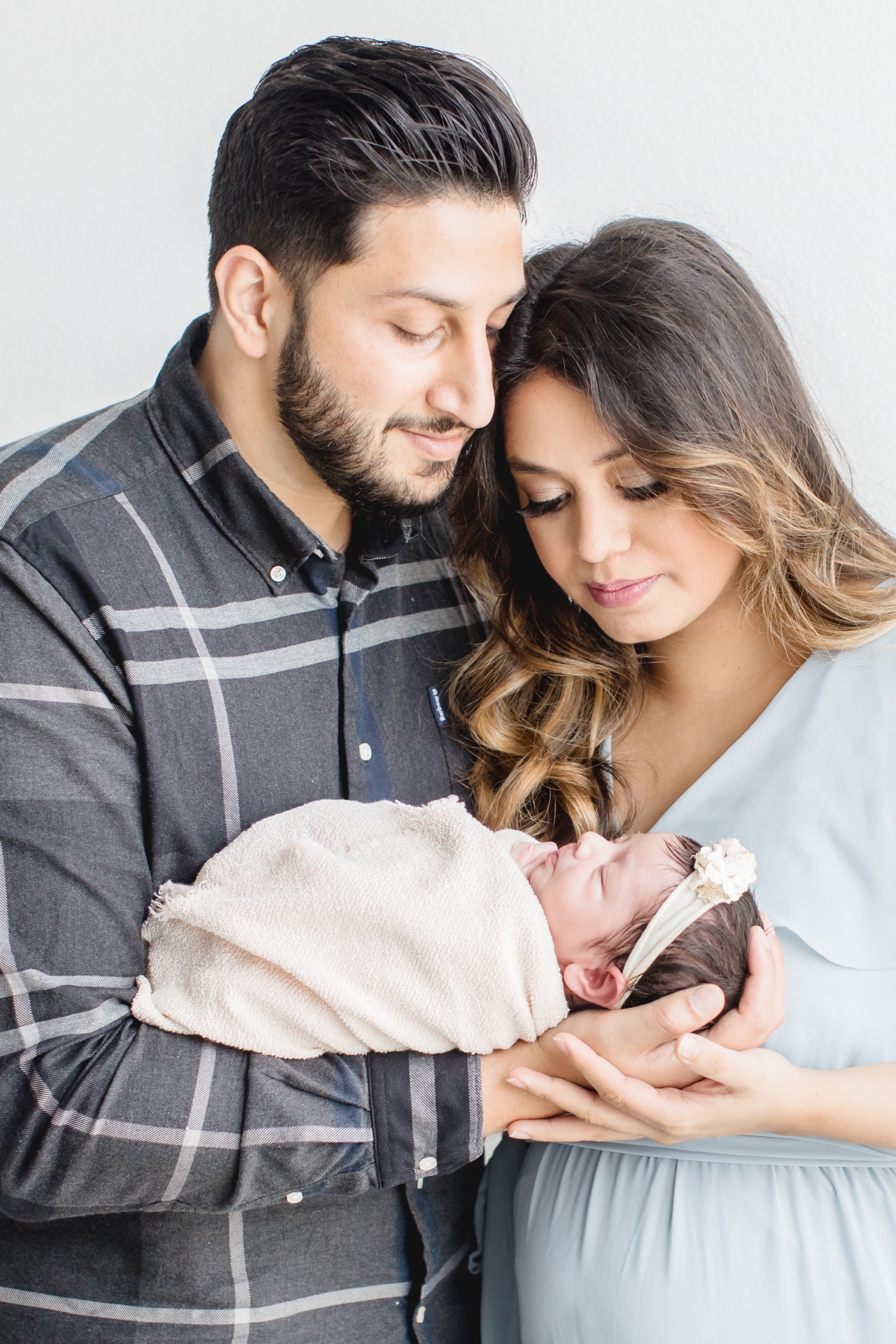 Mom and dad holding baby girl during newborn session. Photo by Sana Ahmed Photography