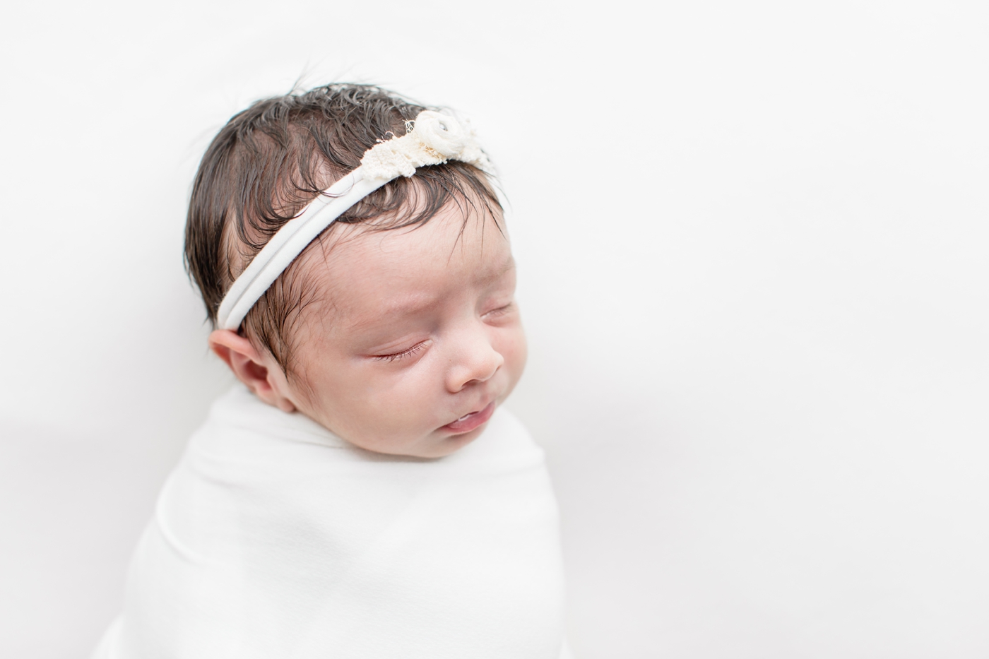 Close up of baby girl in white swaddle during newborn session. Photo by Sana Ahmed Photography