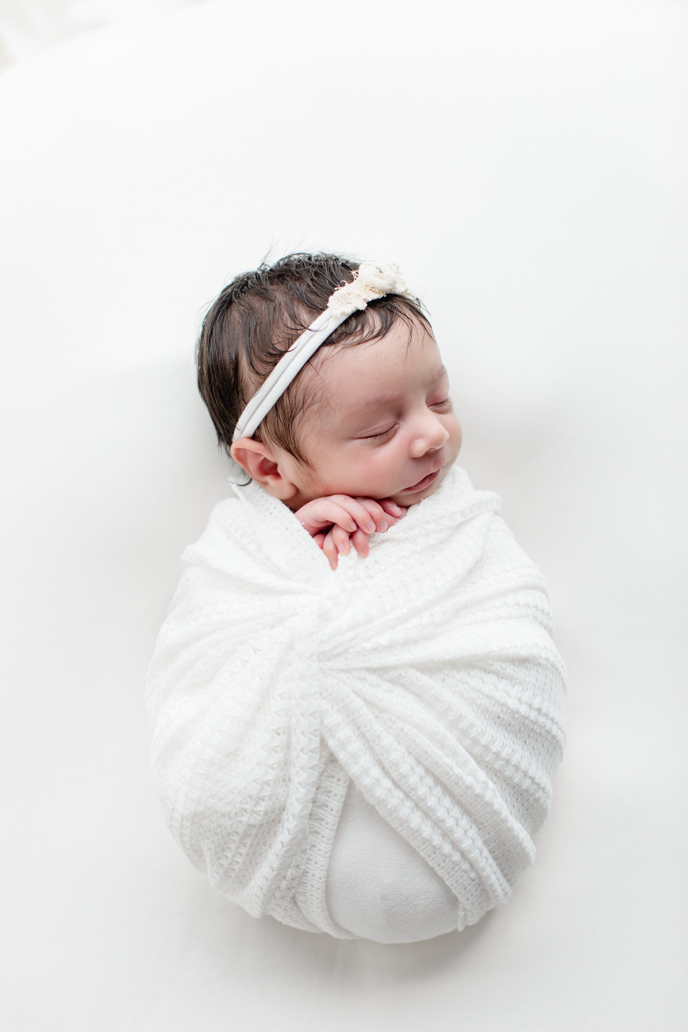 Baby girl in white wrap during studio newborn session in North Austin, TX. Photo by Sana Ahmed Photography