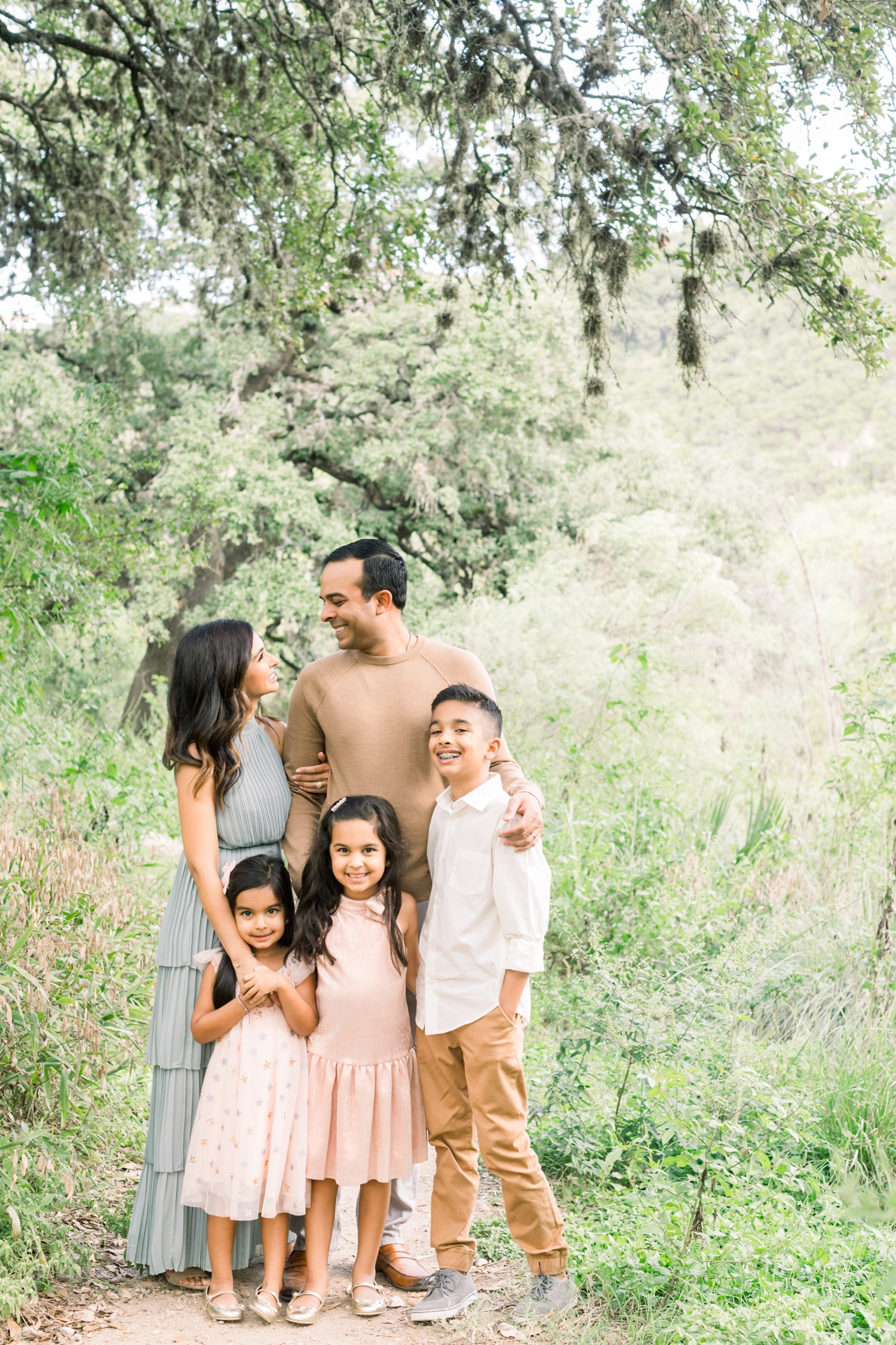 Family with three kids smiling together during field session in Austin TX. Photo by Sana Ahmed Photography.