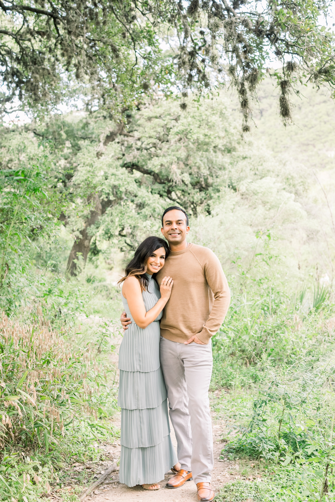 Parents smiling at camera during Austin TX family session. Photo by Sana Ahmed Photography.