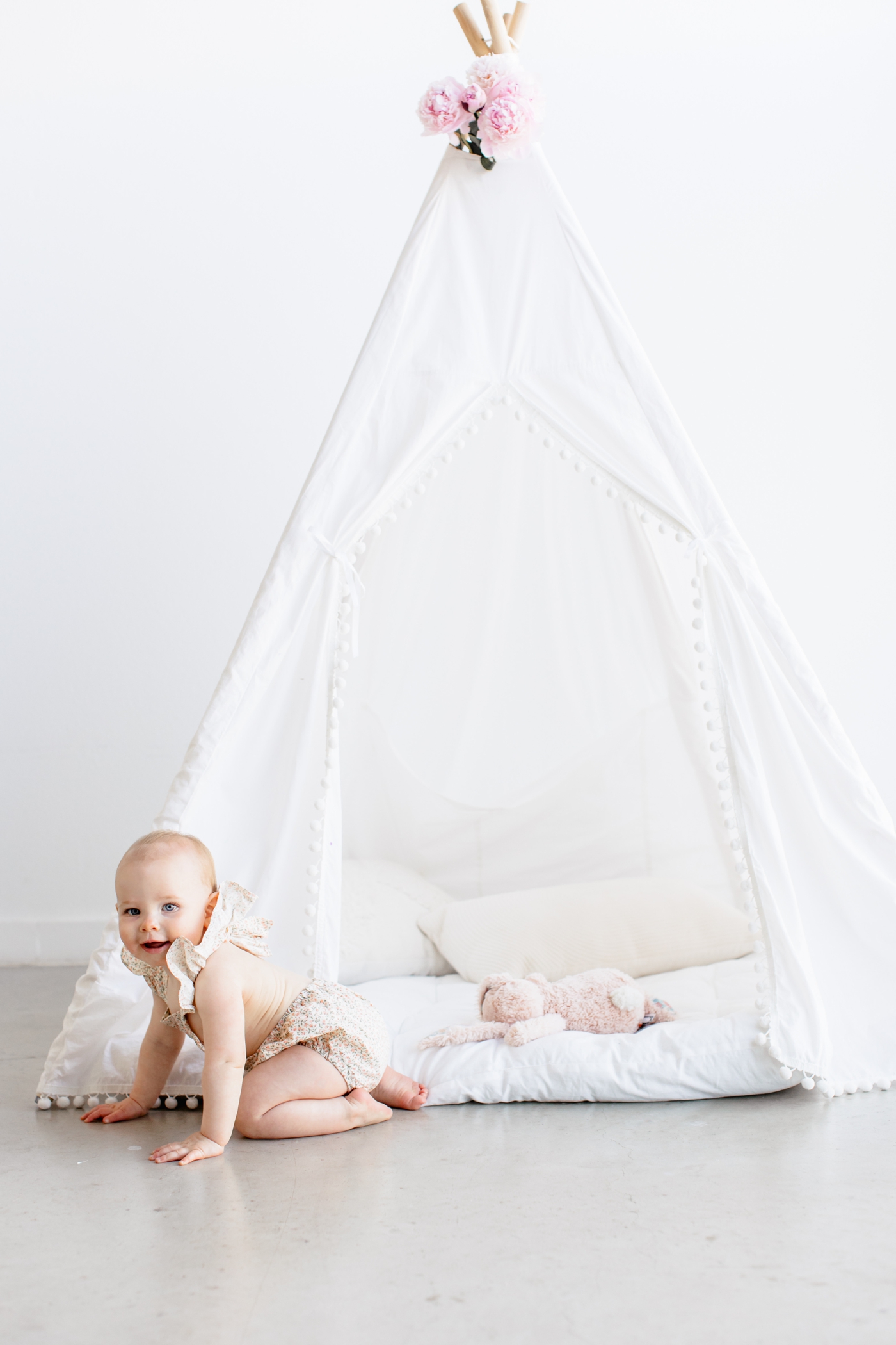 Toddler crawling out of teepee during studio milestone session. Photo by Sana Ahmed Photography.