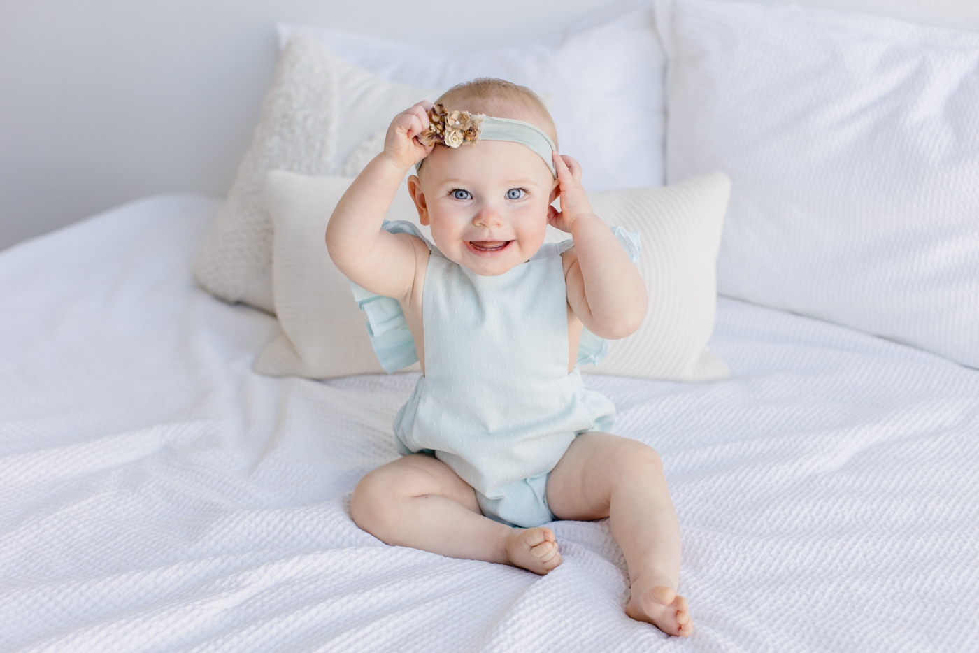 Smiling toddler with floral headband and romper from Client Wardrobe. Photo by Sana Ahmed Photography.