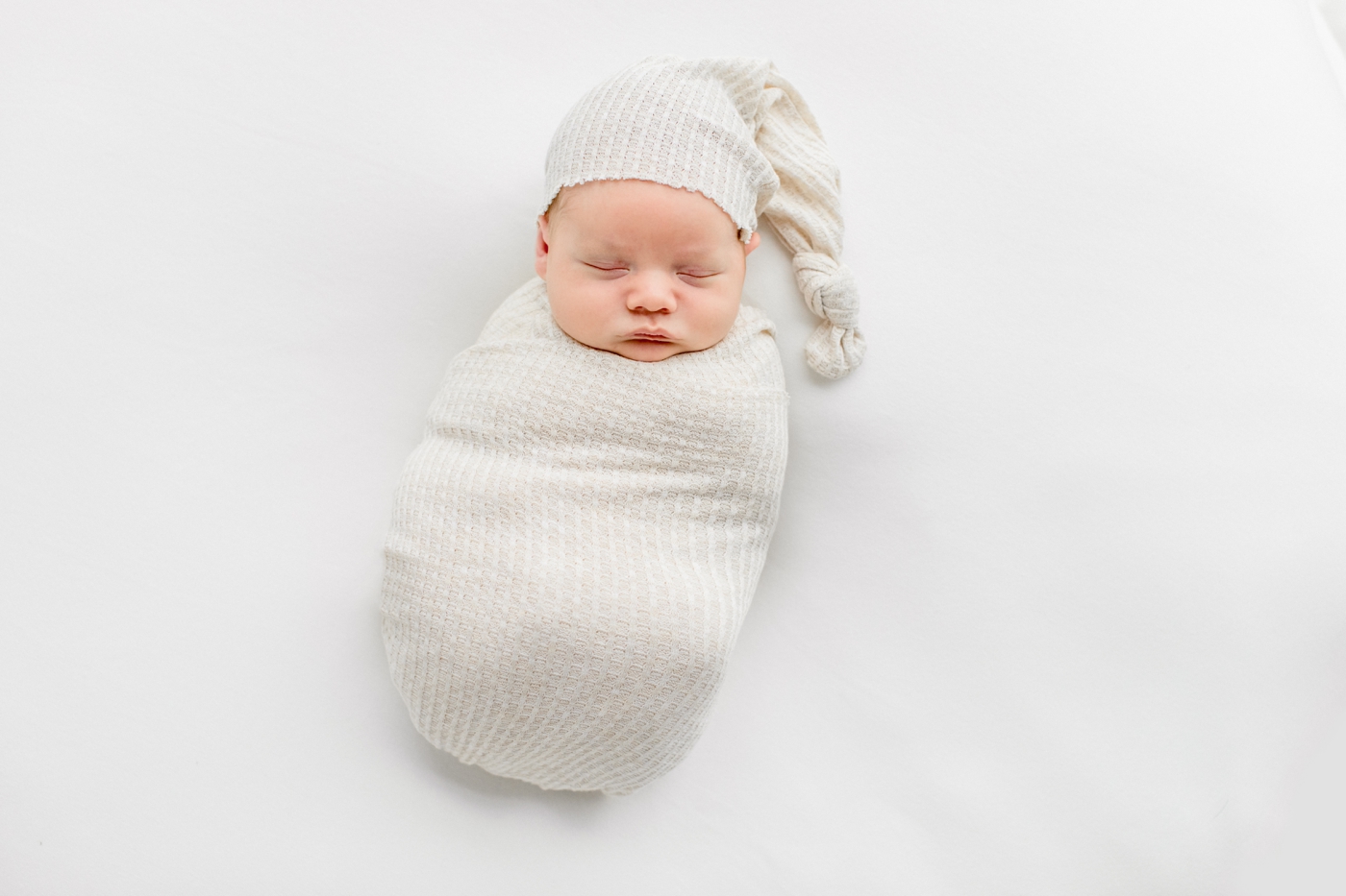 Baby boy sleeping with knit swaddle and hat. Photo by Austin Newborn Photographer, Sana Ahmed Photography.