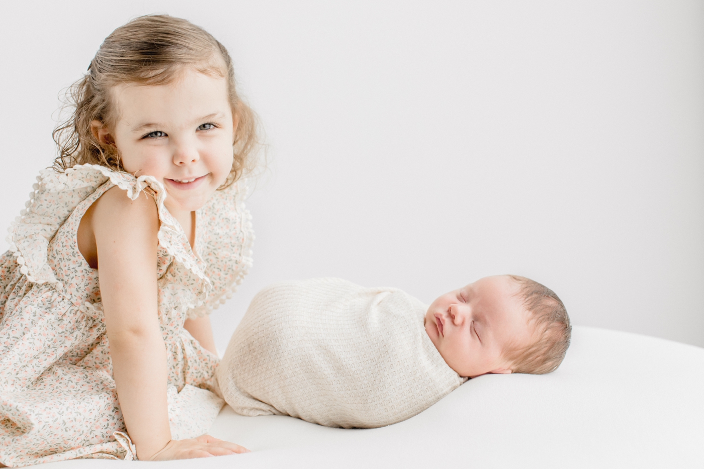 Toddler smiling next to baby brother during newborn session. Photo by Austin Newborn Photographer, Sana Ahmed Photography.