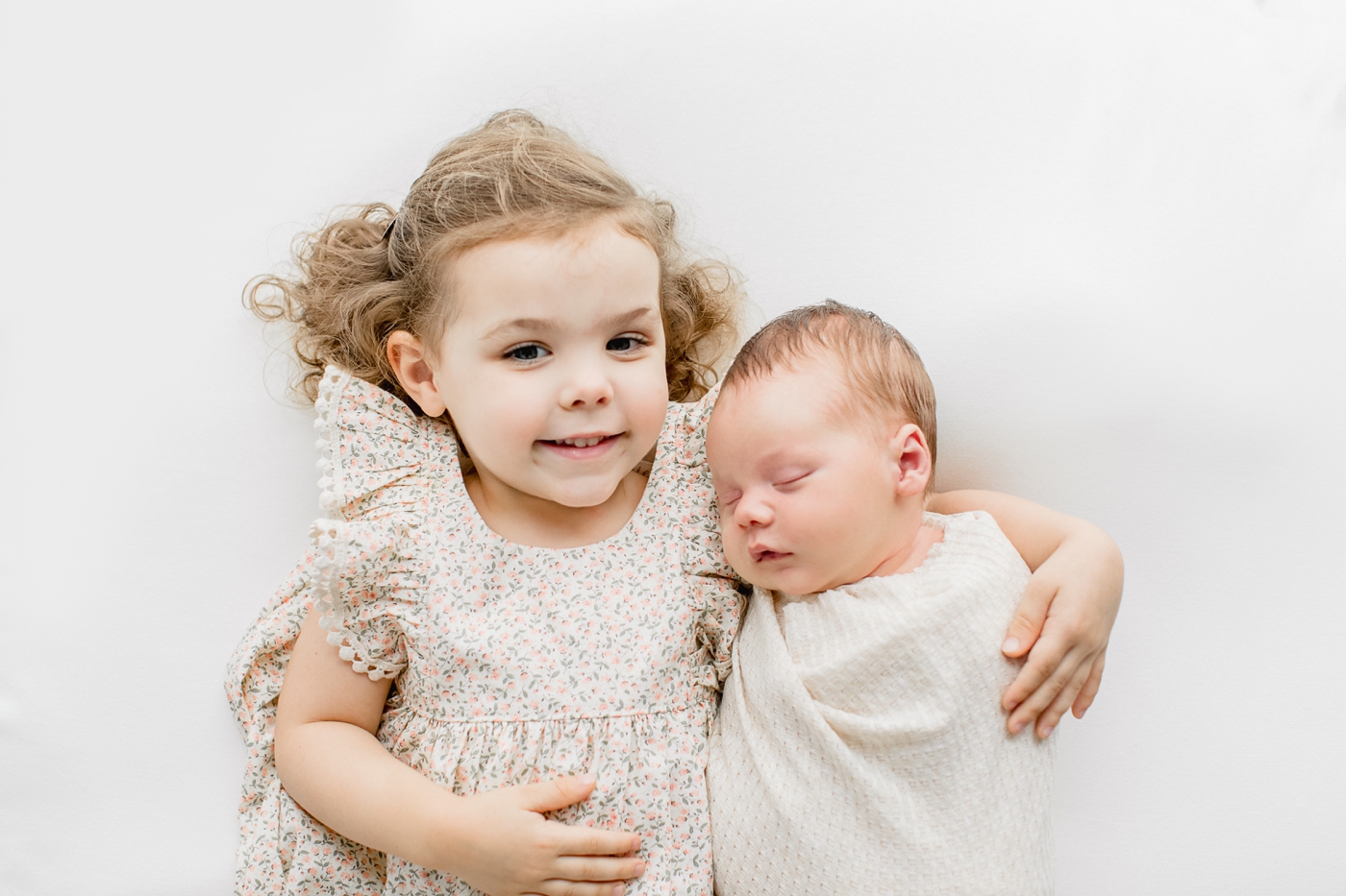 Big sister holding newborn baby brother during in studio newborn session. Photo by Sana Ahmed Photography.