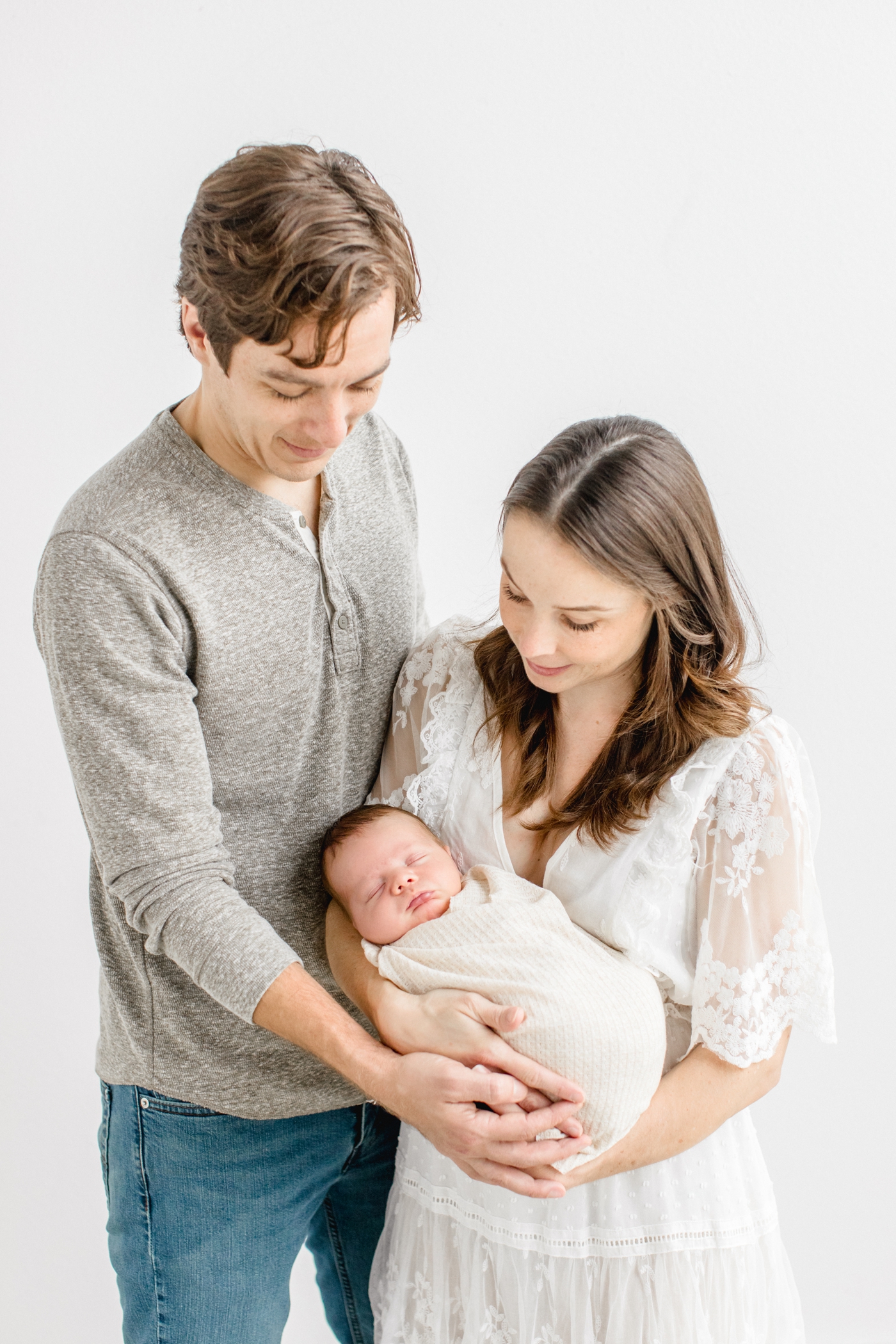 Mom and Dad holding baby during newborn photography session in Austin, TX. Photo by Sana Ahmed Photography.