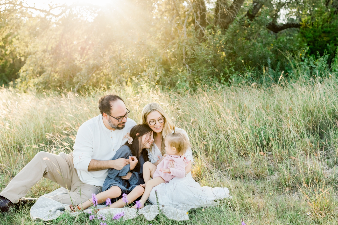 Family cuddling on blanket during Austin, Texas family session. Photo by Sana Ahmed Photography.