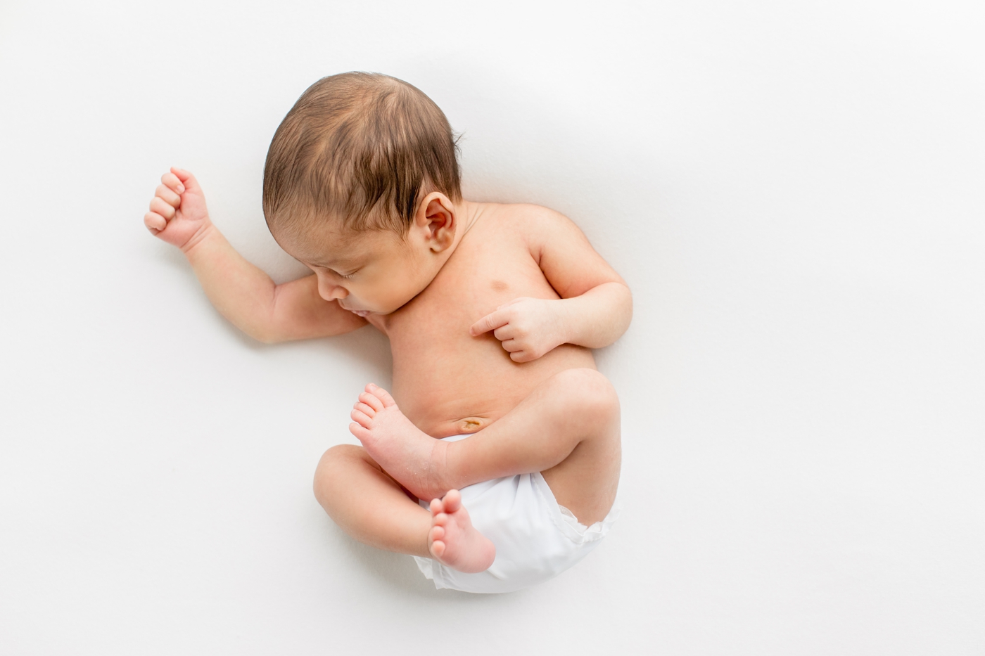 Newborn on white backdrop sleeping by Austin TX baby photographer, Sana Ahmed Photography.
