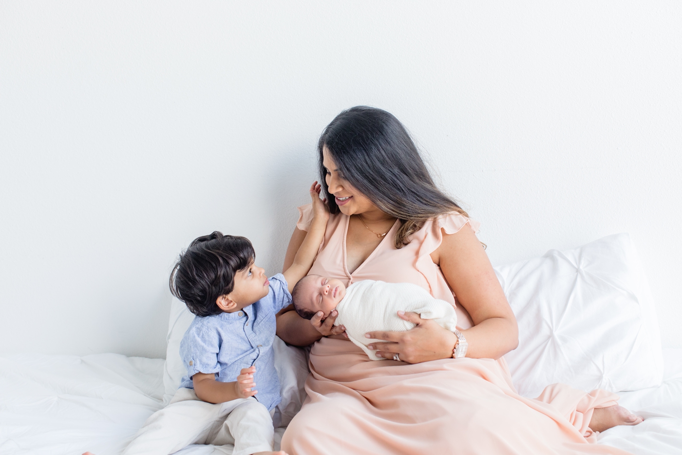 Sweet moment between toddler and Mom looking at each other during newborn session. Photo by Sana Ahmed Photography.