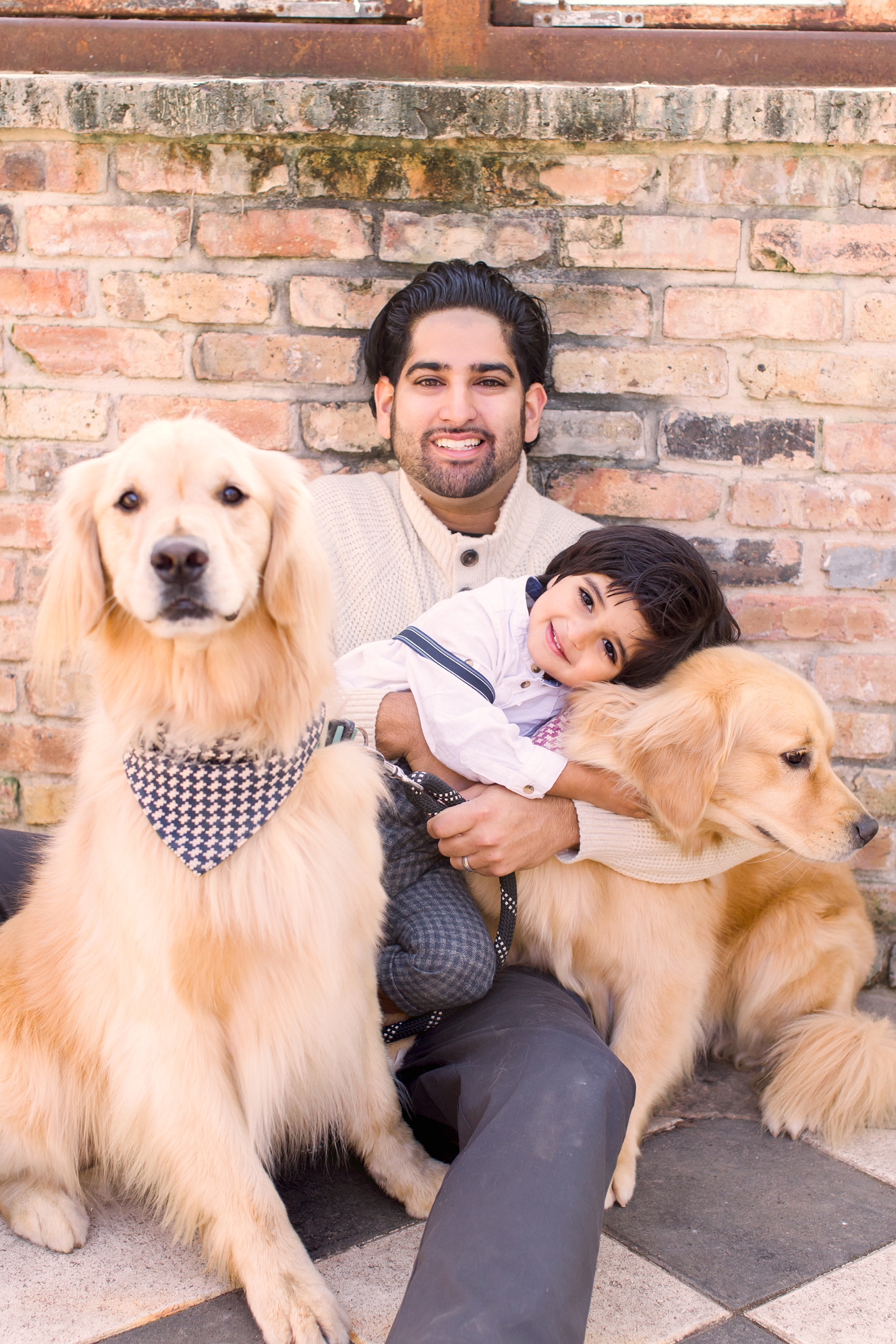 Dad and son cuddling two dogs during family session in Austin, TX. Photo by Sana Ahmed Photography.