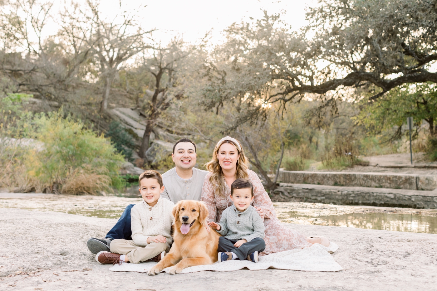 Sweet family photo with two kids and dog near creek in Austin, TX. Photo by Sana Ahmed Photography.