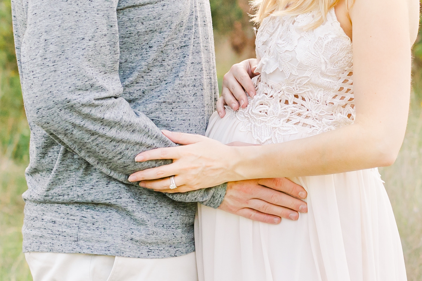 Closeup of parents hugging baby bump in maternity photoshoot. Photo by Sana Ahmed Photography.
