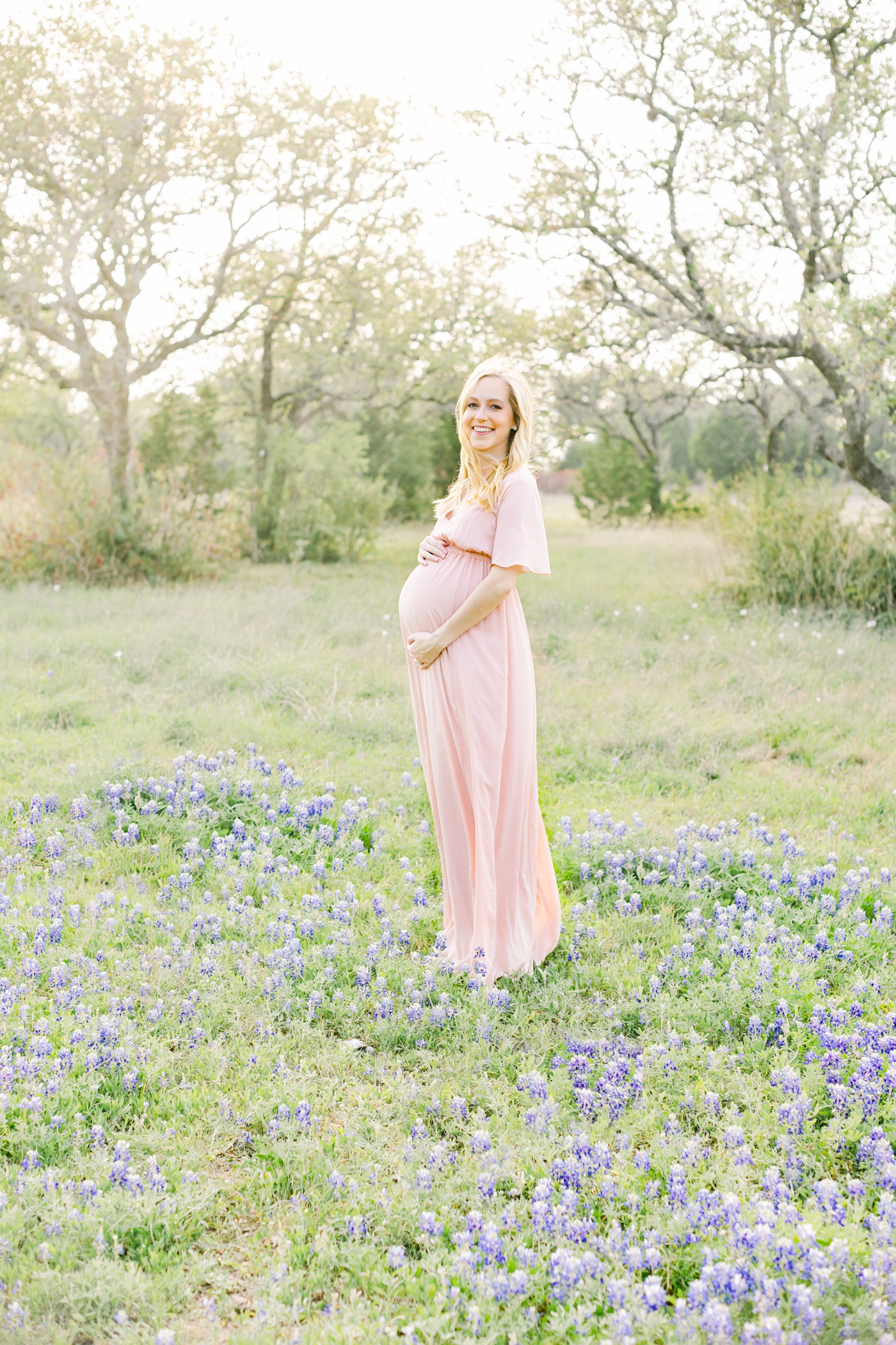 Mom standing in bluebonnets during maternity session in Austin. Photo by Sana Ahmed Photography.