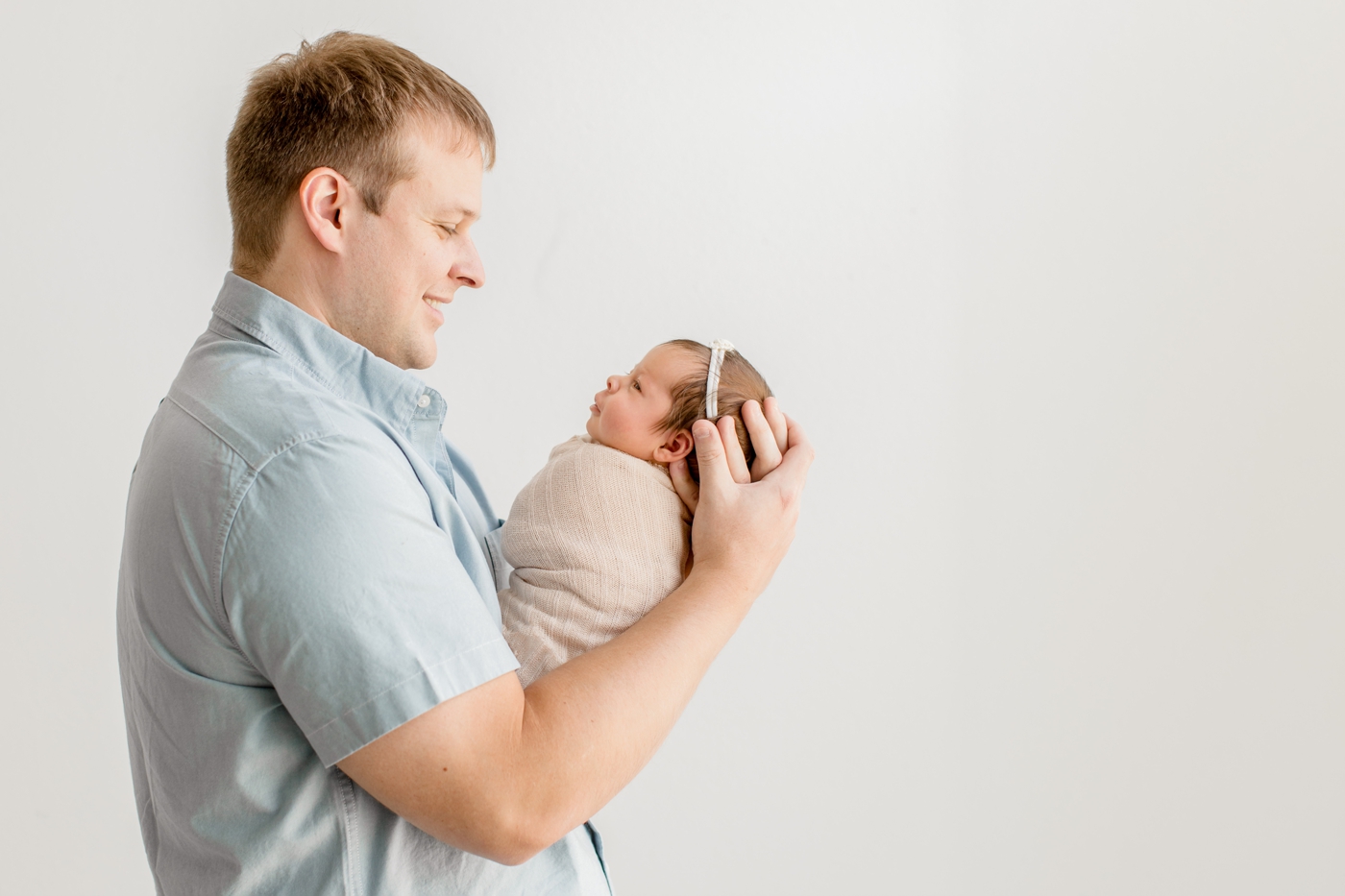 Dad holding baby as they look at each other during newborn session. Photo by Sana Ahmed Photography.