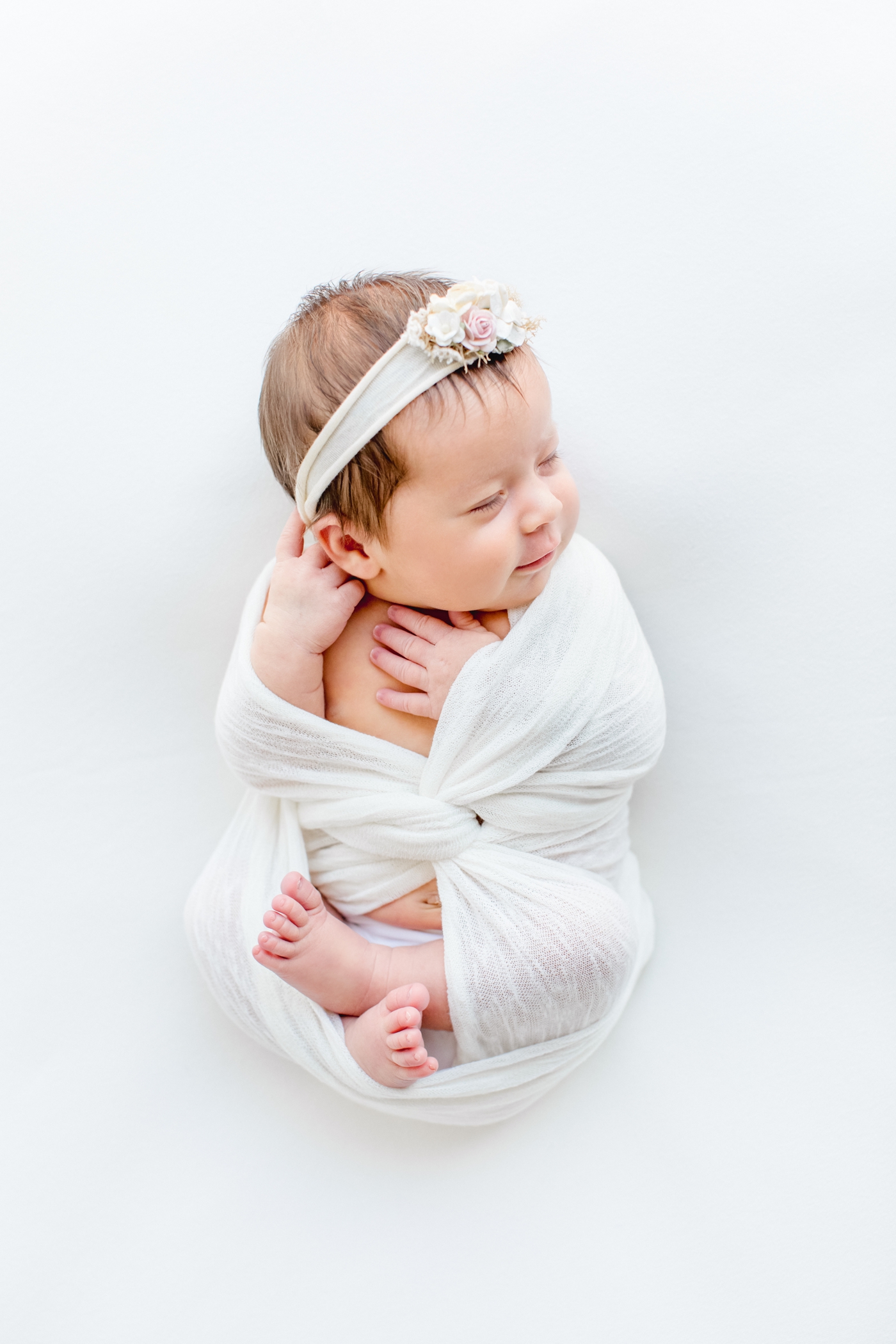Smiling newborn in white swaddle during Austin TX studio newborn session. Photo by Austin TX baby photographer, Sana Ahmed Photography.