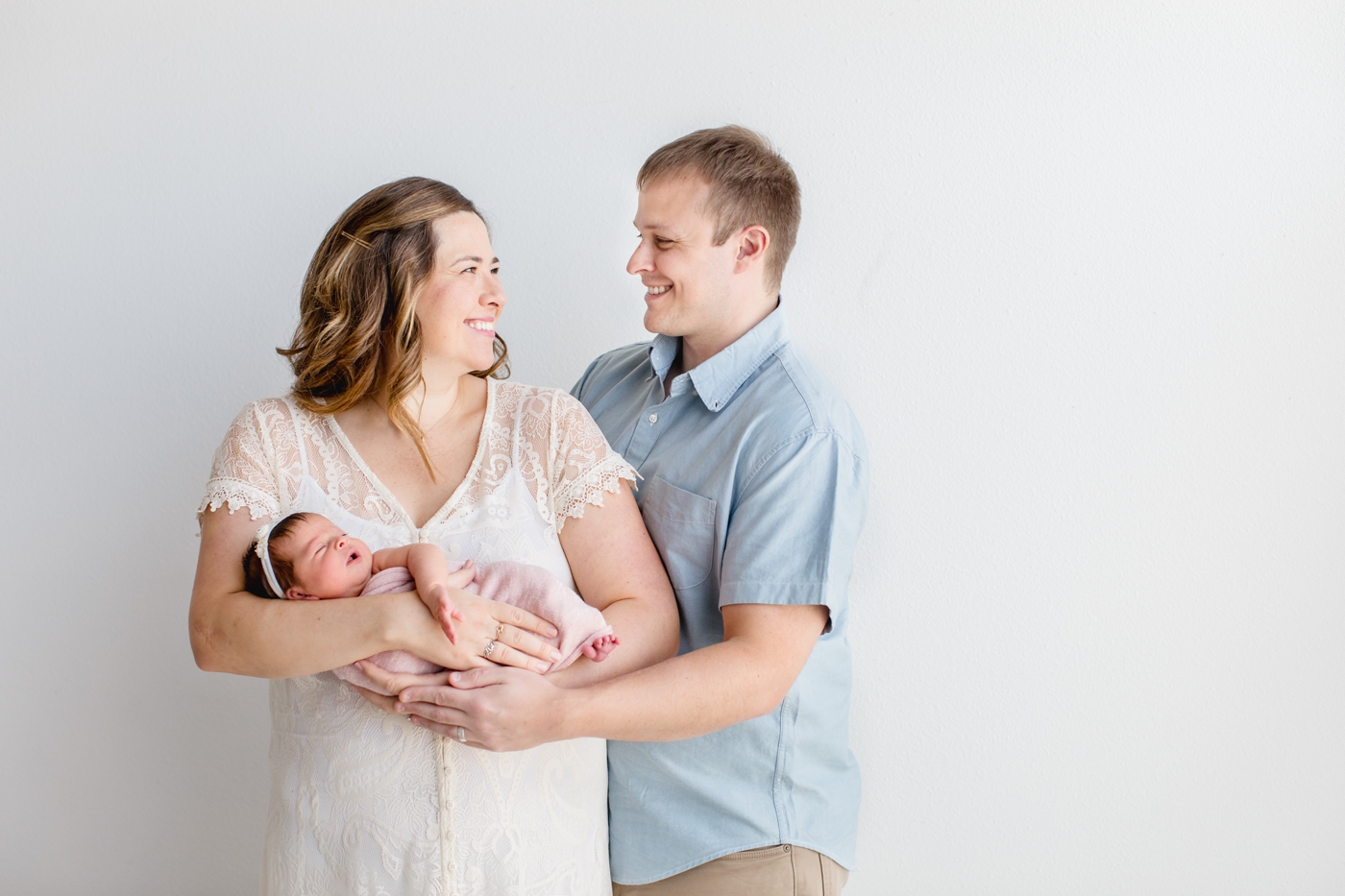 Mom and Dad smiling at each other during studio newborn session in Austin TX. Photo by Sana Ahmed Photography.