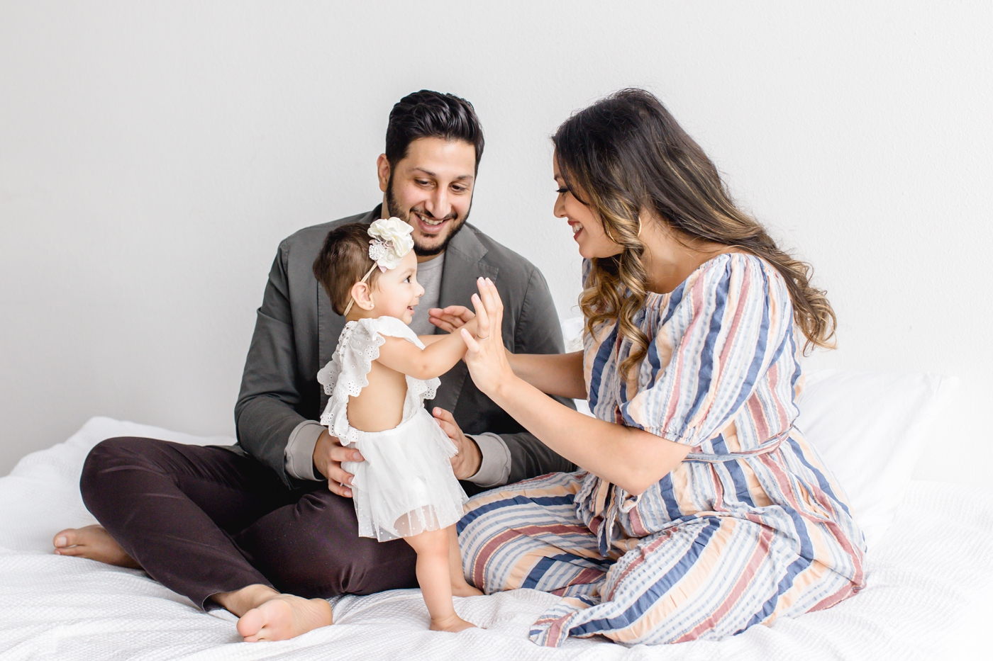 Sweet candid photo of parents playing with baby girl during milestone session. Photo by Cedar Park family photographer, Sana Ahmed Photography.
