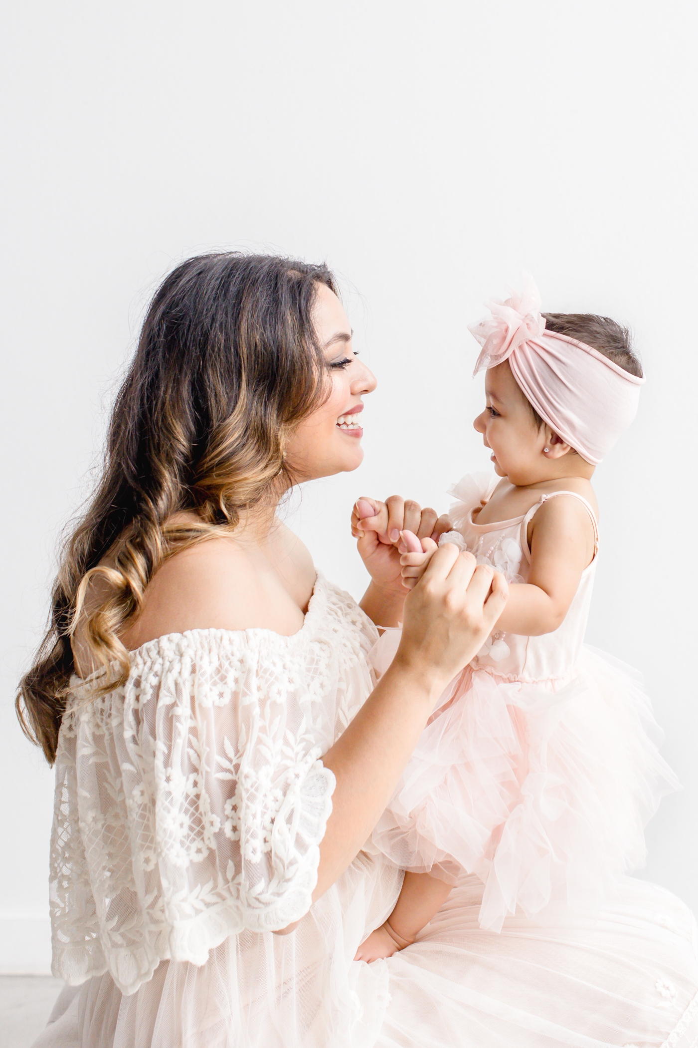 Mom holding baby and smiling during studio session. Photo by Cedar Park family photographer, Sana Ahmed Photography.