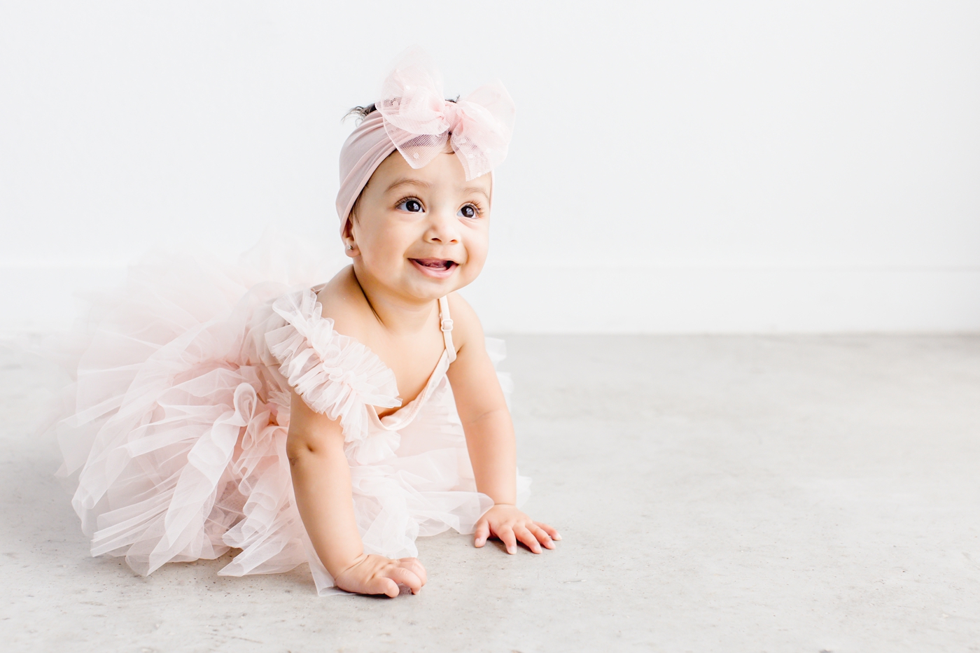 Baby girl beginning to crawl in pink tulle tutu outfit during family photos in Cedar Park. Photo by Sana Ahmed Photography.