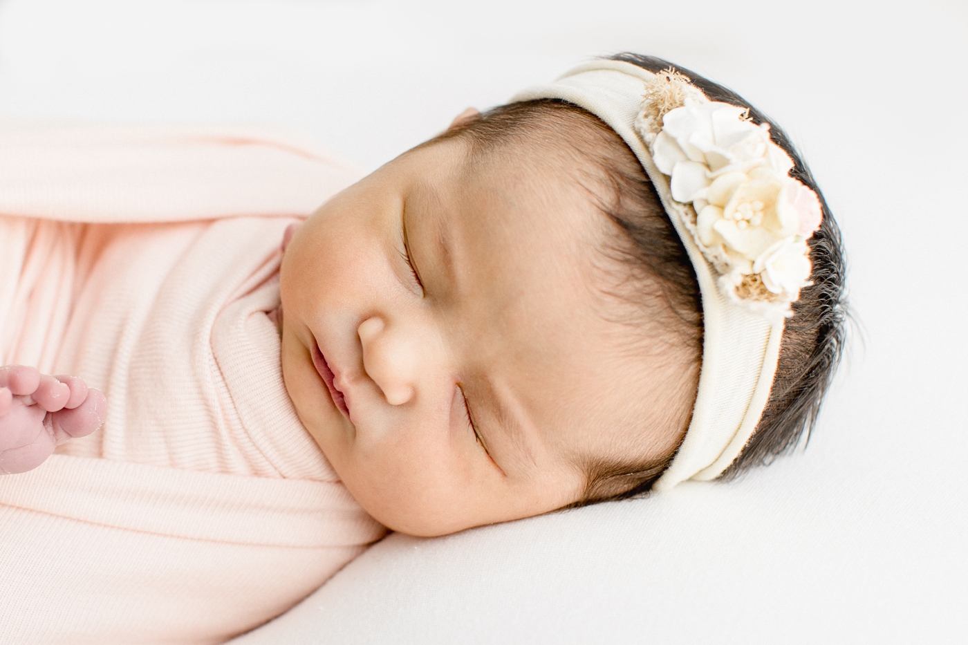 Closeup of baby's facial features while wearing floral headband. Photo by Cedar Park newborn photographer, Sana Ahmed Photography.