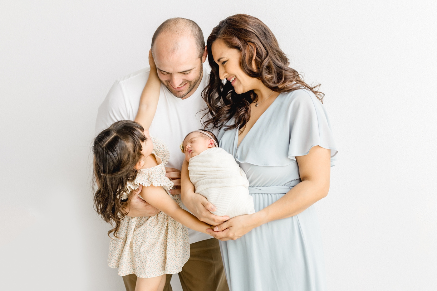 Sweet moment with older sibling look at Dad while Mom holds baby. Photo by Cedar Park newborn photographer, Sana Ahmed Photography.