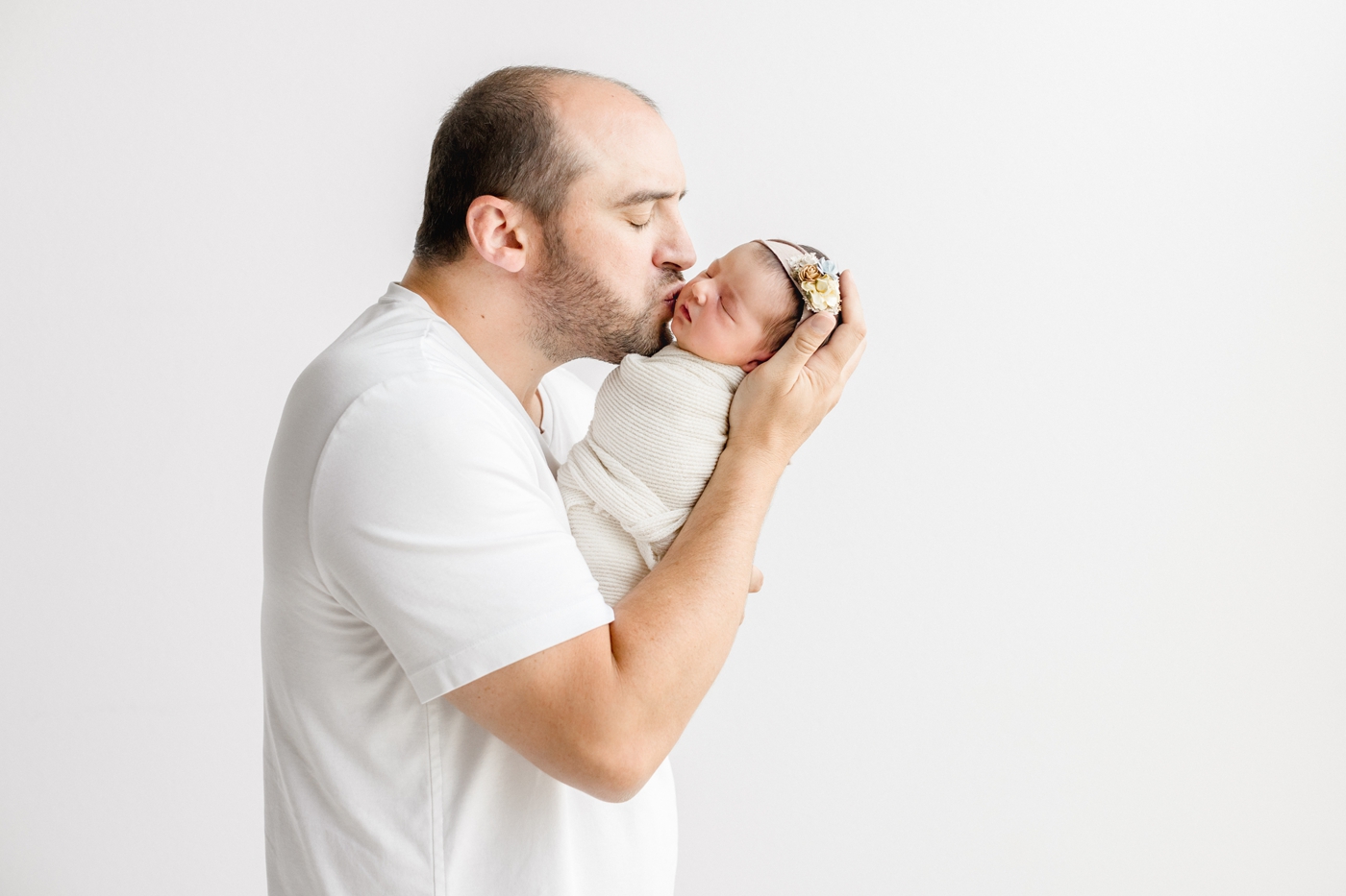 Dad kissing baby girl during newborn session. Photo by Sana Ahmed Photography.