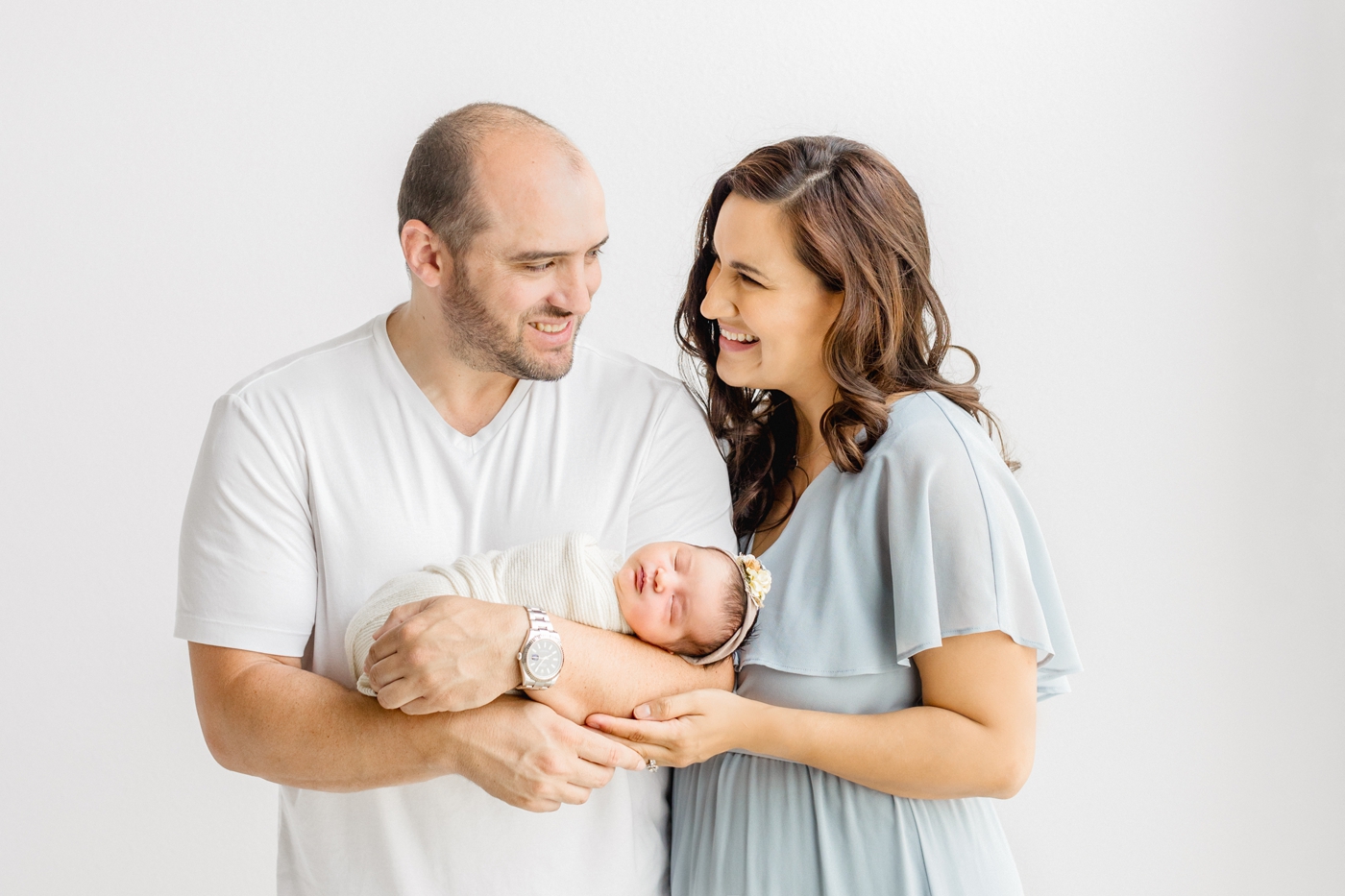 Mom and Dad smiling at each other in studio newborn session near Cedar Park TX.Photo by Sana Ahmed Photography.