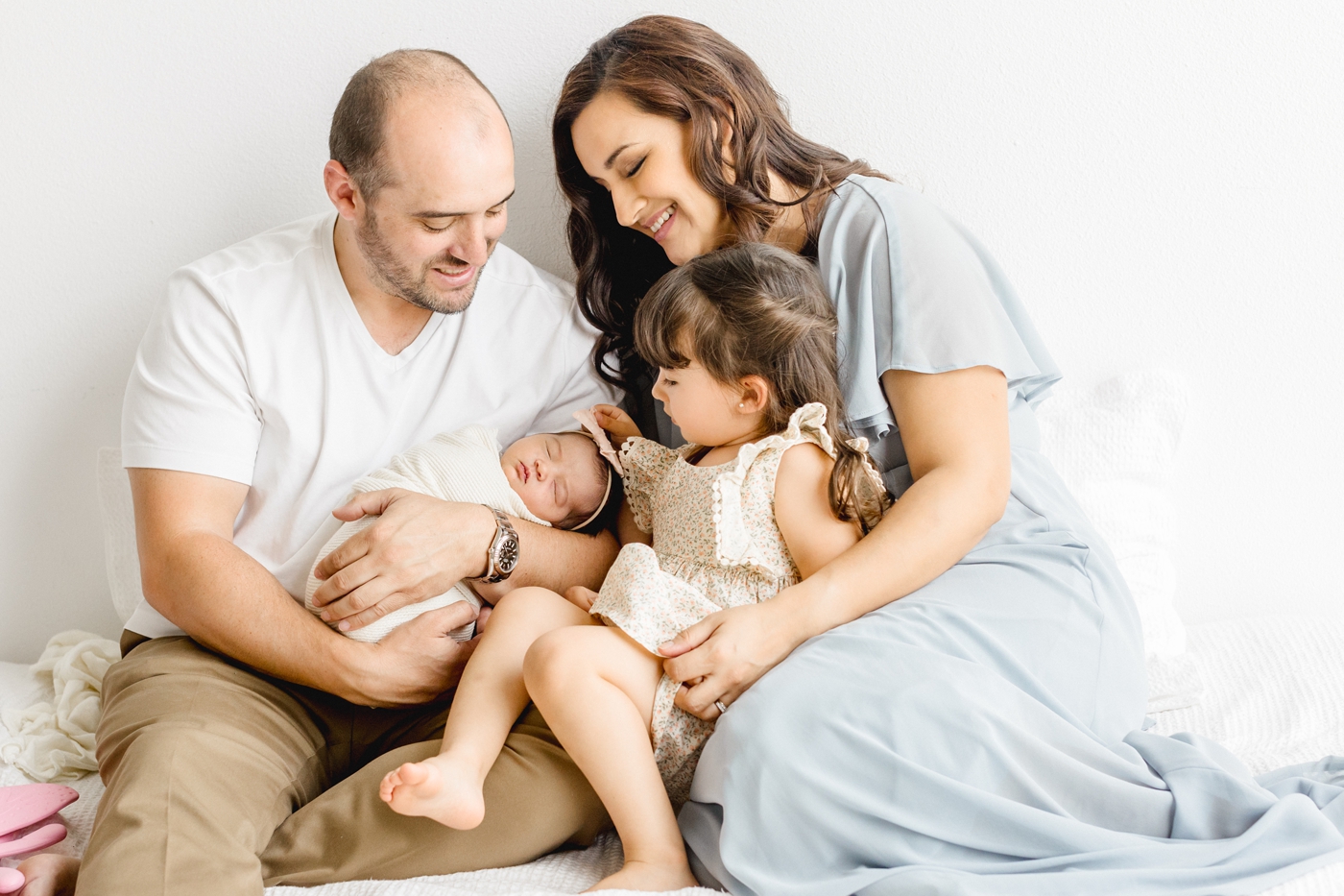 Family looking at baby during studio newborn session with sibling. Photo by Cedar Park newborn photographer, Sana Ahmed Photography.