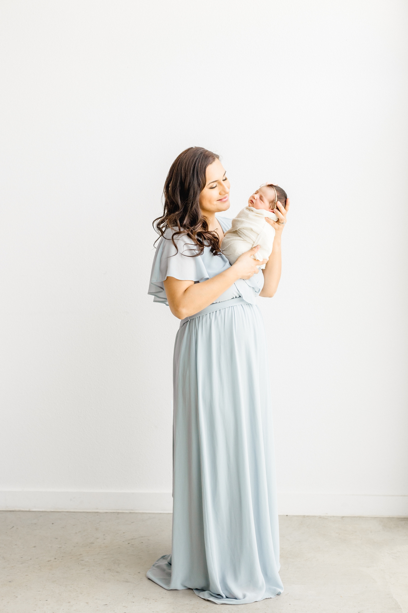 Mom holding swaddled baby during Cedar Park newborn session. Photo by Sana Ahmed Photography.