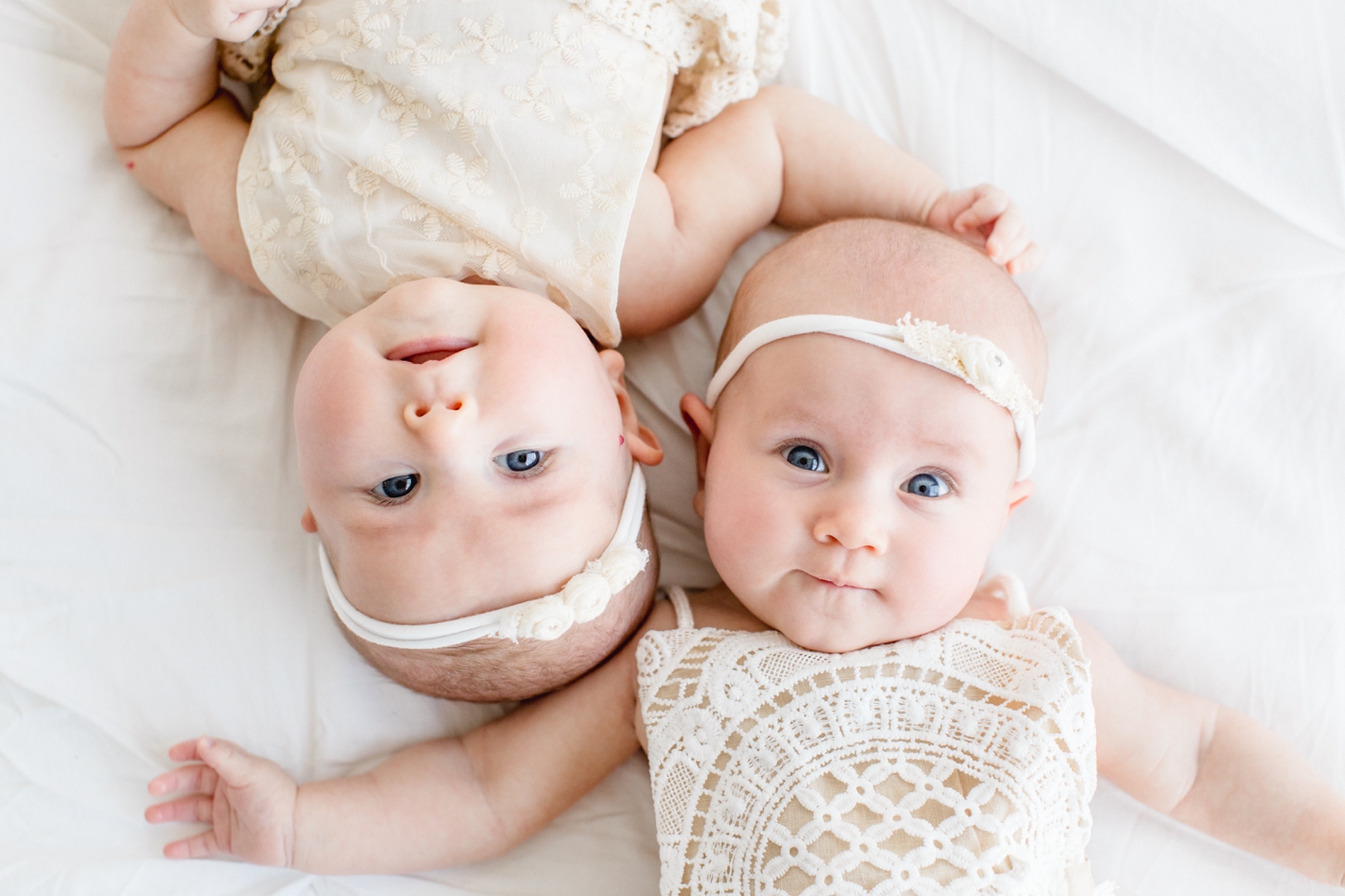Twin baby girls at 3 months with lace rompers on during family session in Austin TX. Photo by Sana Ahmed Photography.
