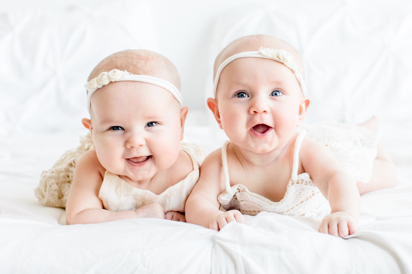 Twin girls smiling at camera while doing tummy time. Photo by Austin family photographer, Sana Ahmed Photography.