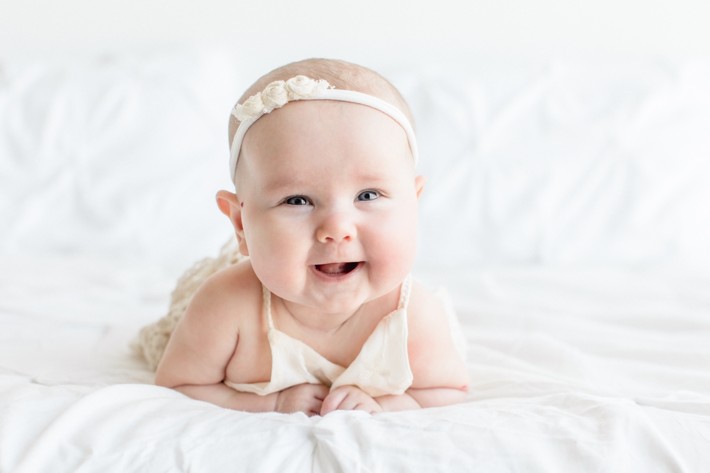 Baby girl doing tummy time and smiling during studio family session in Austin, TX. Photo by Sana Ahmed Photography.
