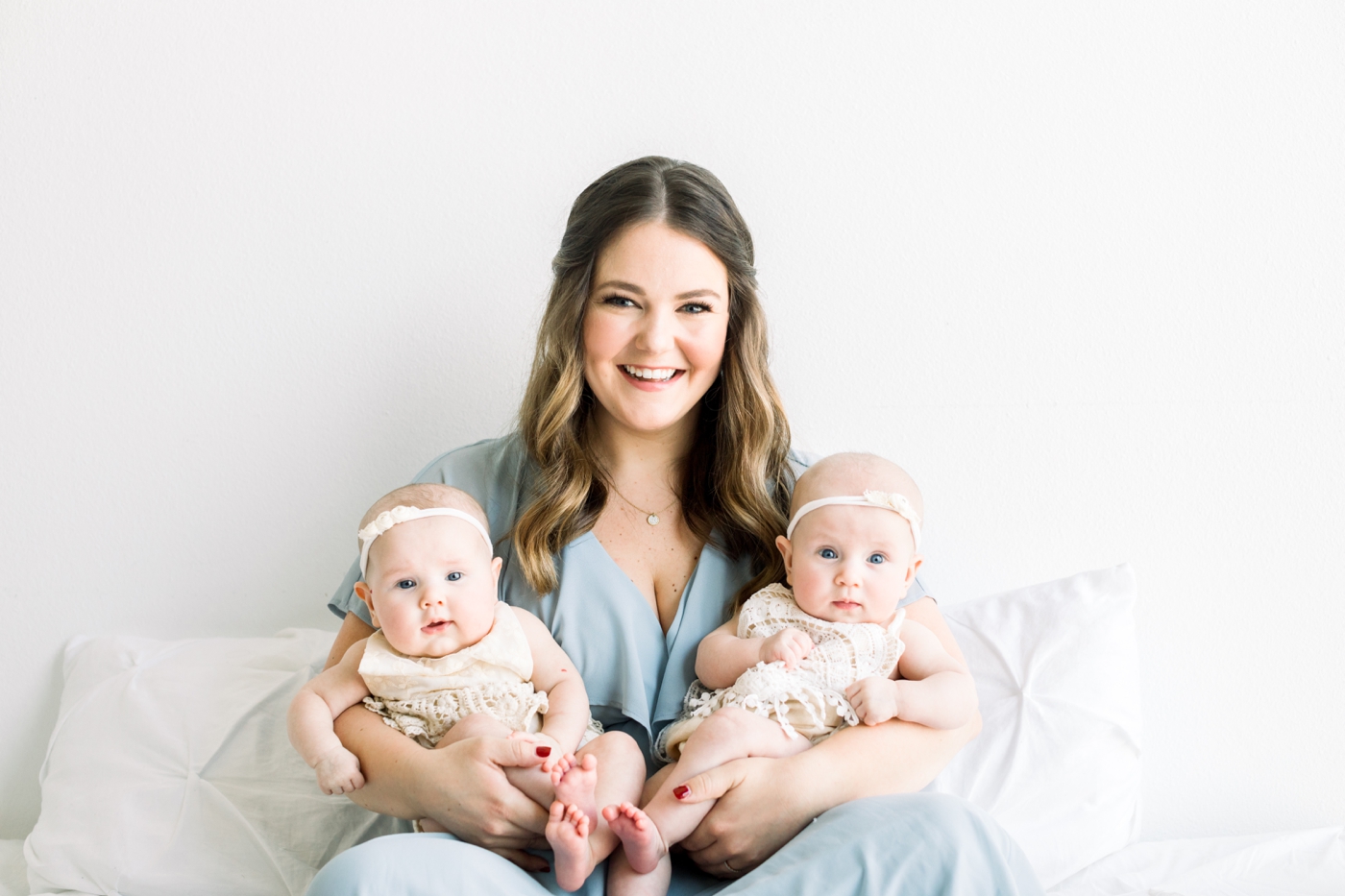 Mom holding twin girls and smiling at camera. Photo by Austin family photographer, Sana Ahmed Photography.