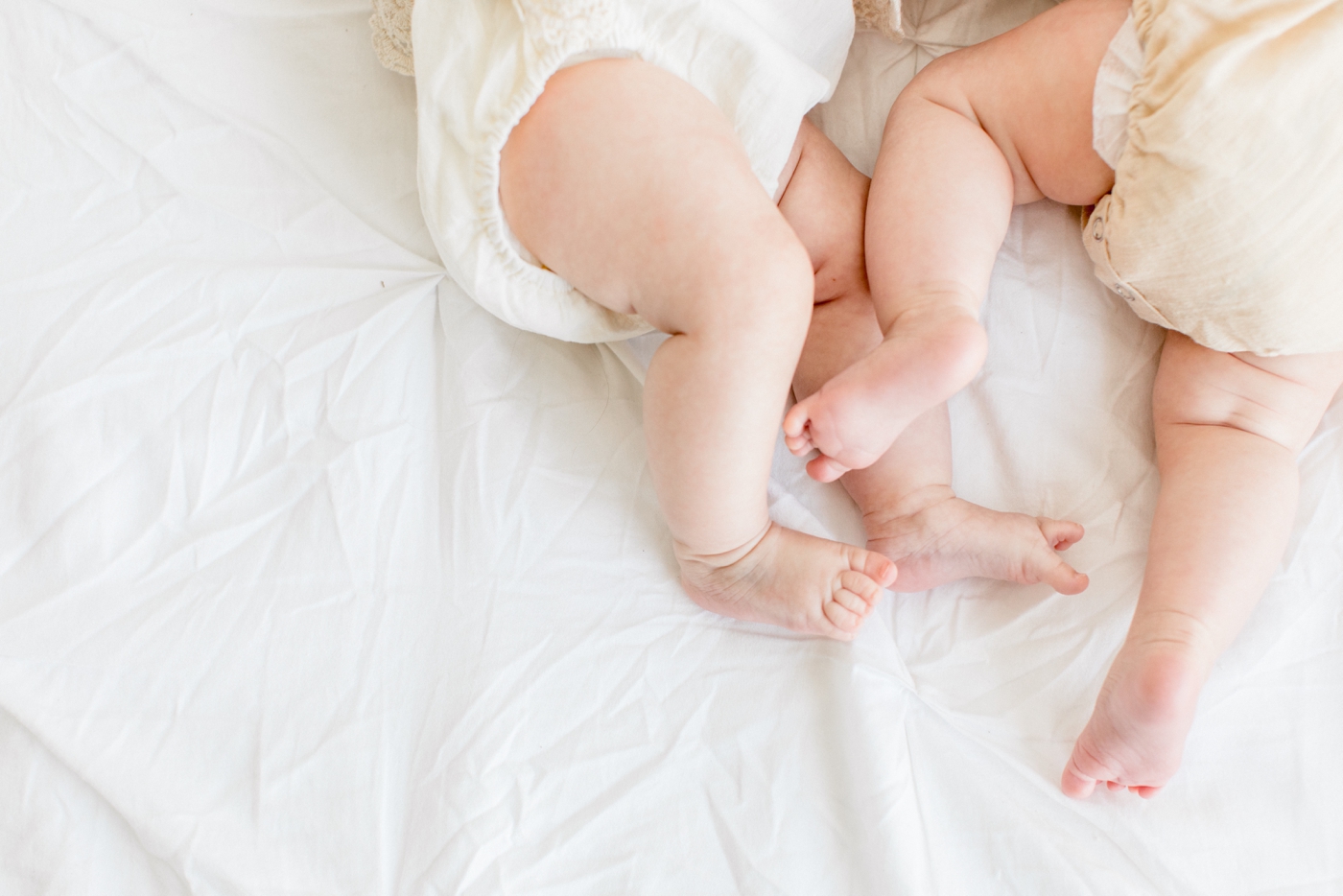 Closeup of feet of twin baby girls wearing lace rompers. Photo by Sana Ahmed Photography.
