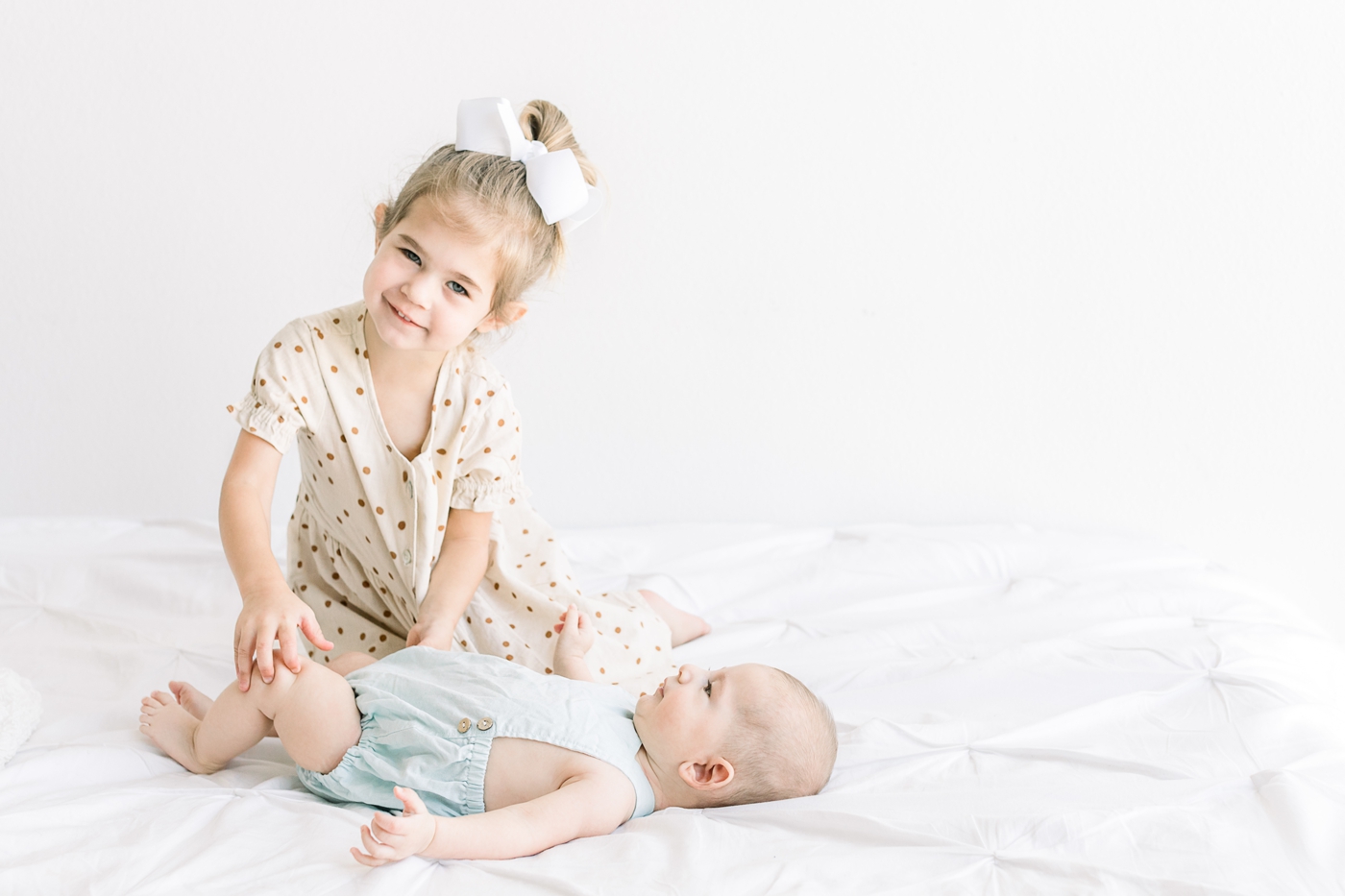Sweet big sister playing with baby brother during family photos in Austin studio. Photo by Sana Ahmed Photography.