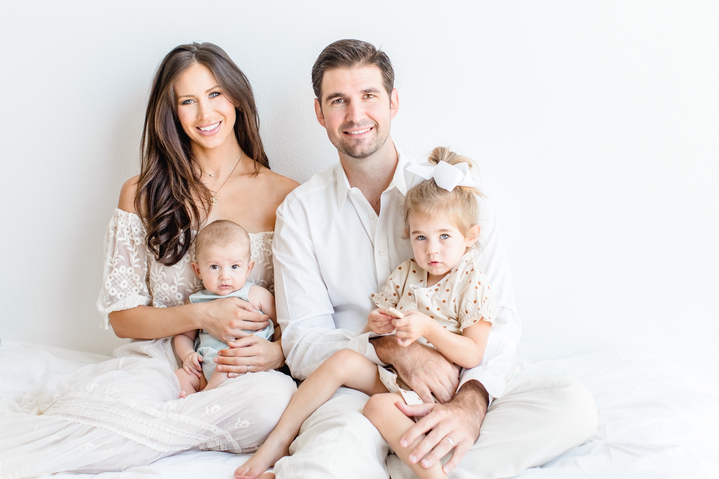 Family of four smiling at camera in North Austin studio. Photo by Sana Ahmed Photography.