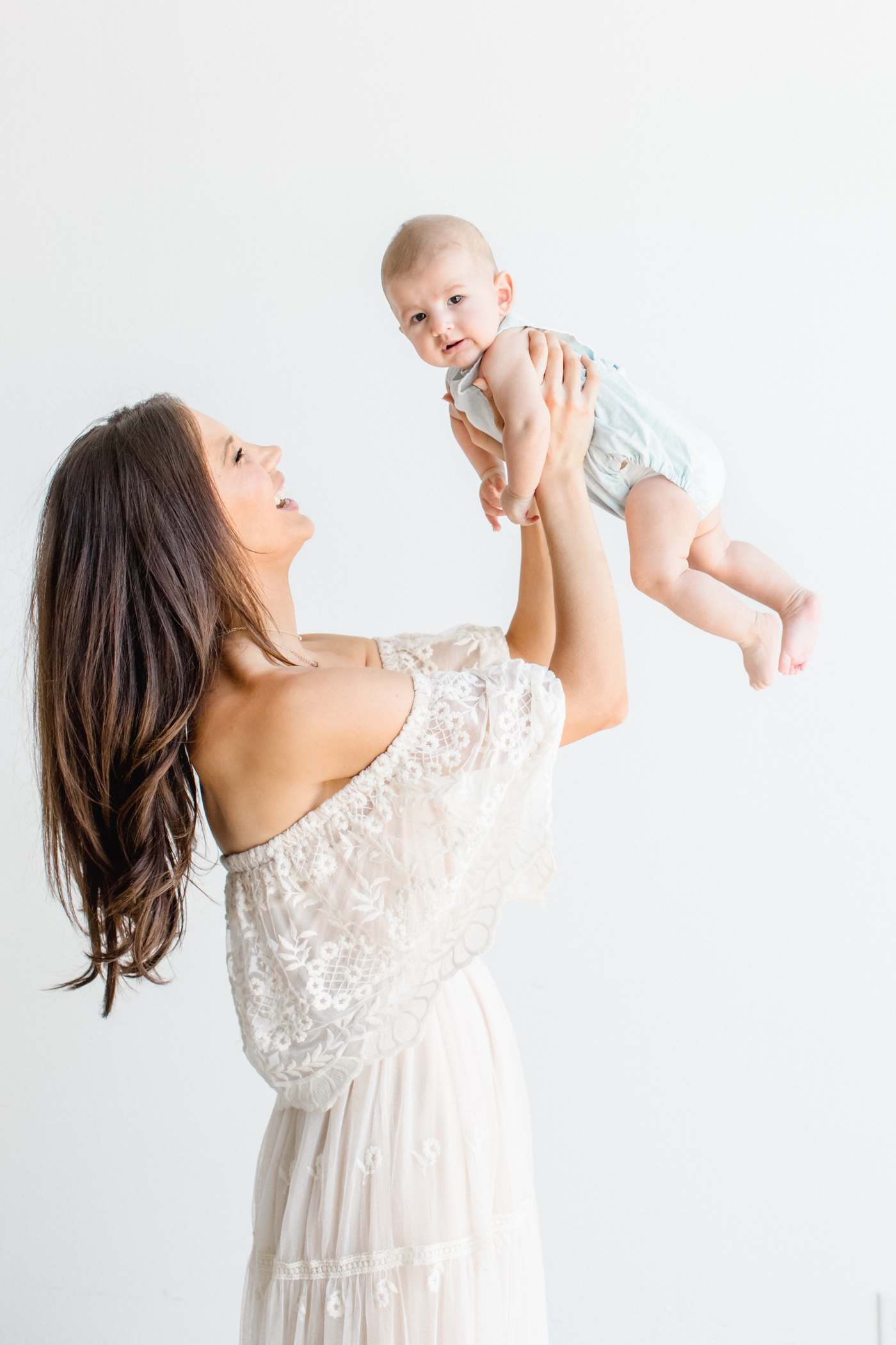 Mom holding baby boy and playing airplane during family photoshoot in Austin, TX. Photo by Sana Ahmed Photography.
