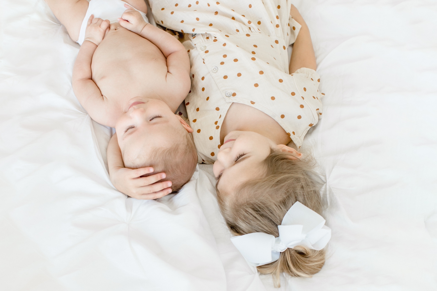 Sweet sister hugging baby brother as he lays on her arm. Photo by Austin TX family photographer, Sana Ahmed Photography.