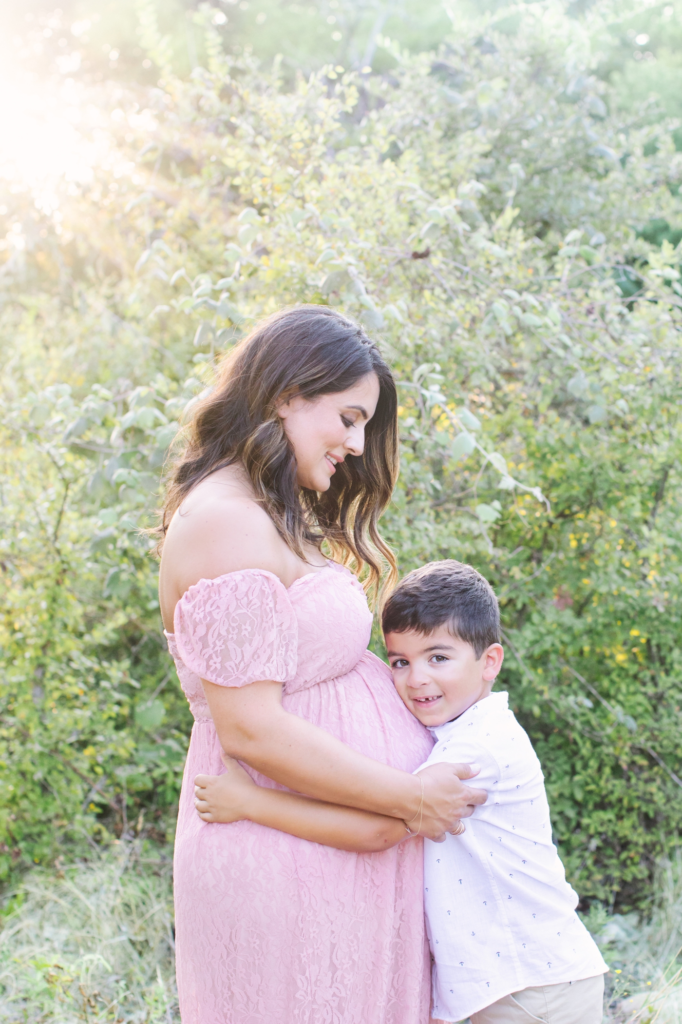 Closeup of big brother hugging on Mom's bump during maternity photos in Austin. Photo by Sana Ahmed Photography.
