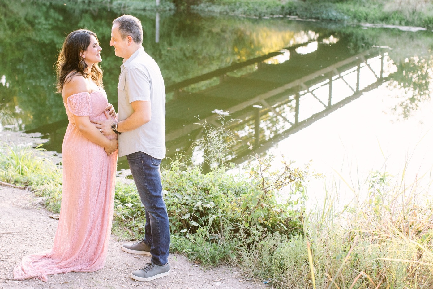 Mom and Dad looking at each other during maternity session in Austin park near the water. Photo by Sana Ahmed Photography.