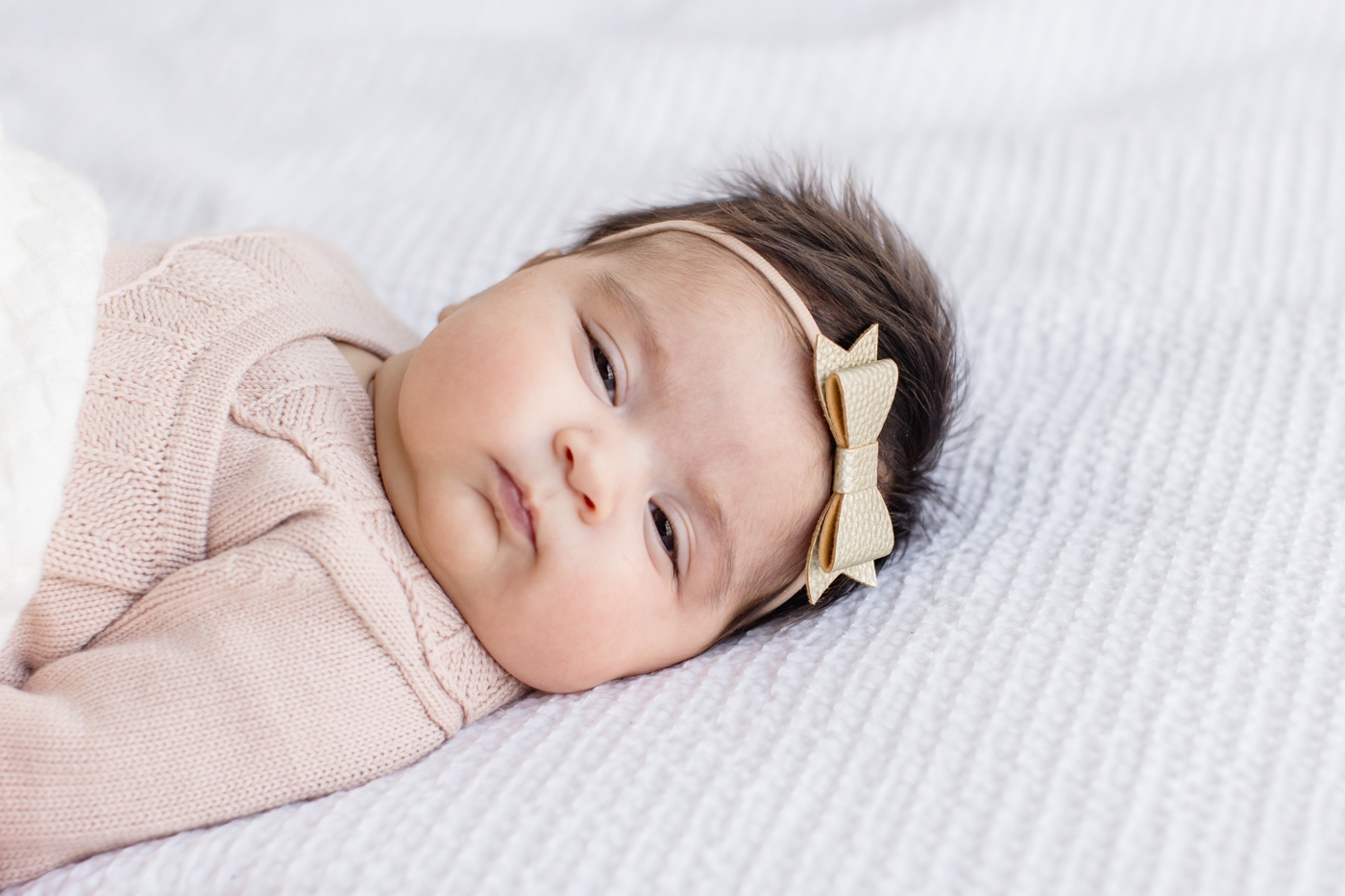 Adorable baby with chunky cheeks wearing pink knit outfit. Photo by Sana Ahmed Photography.