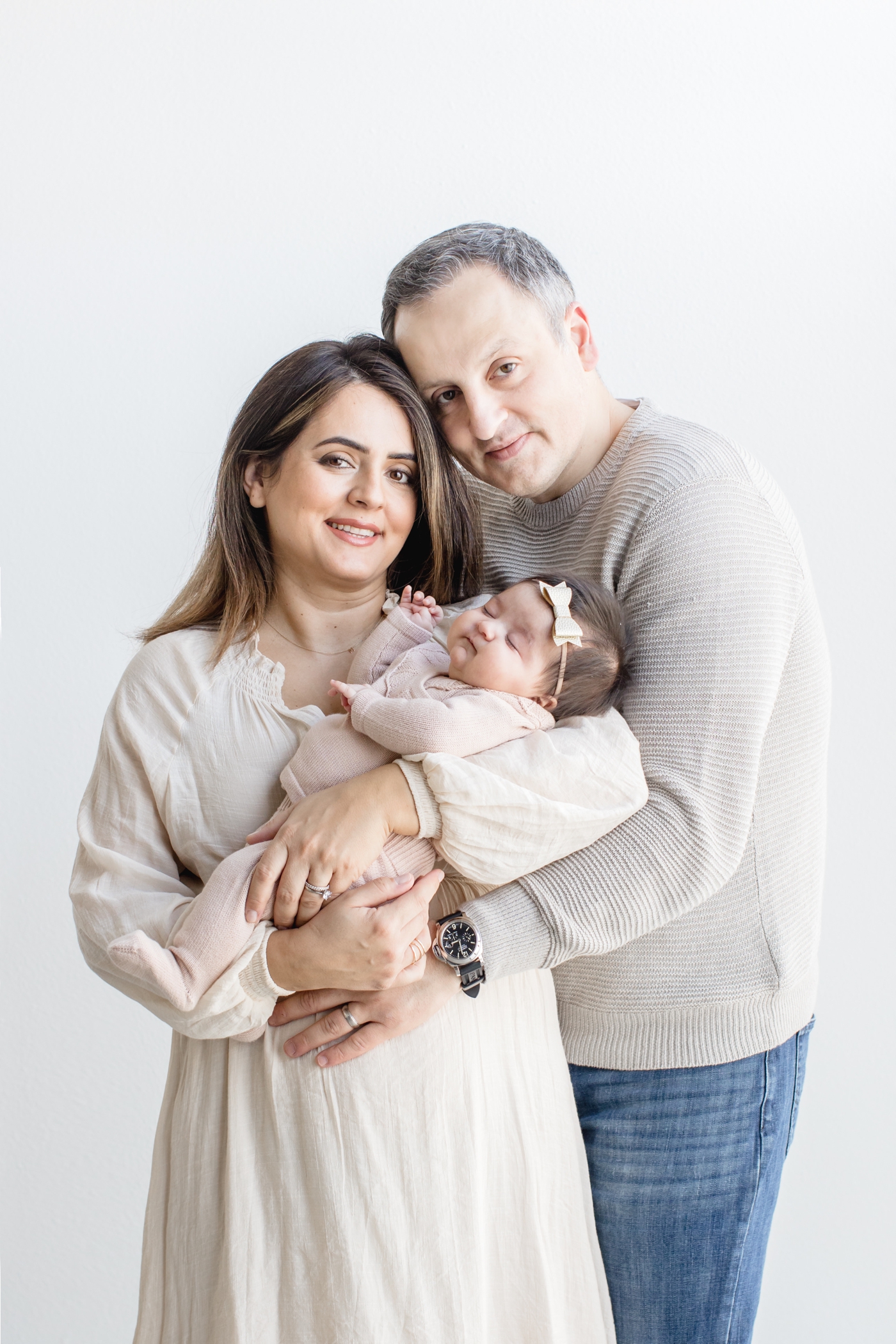 Mom and Dad posing with baby in studio session with Sana Ahmed Photography.