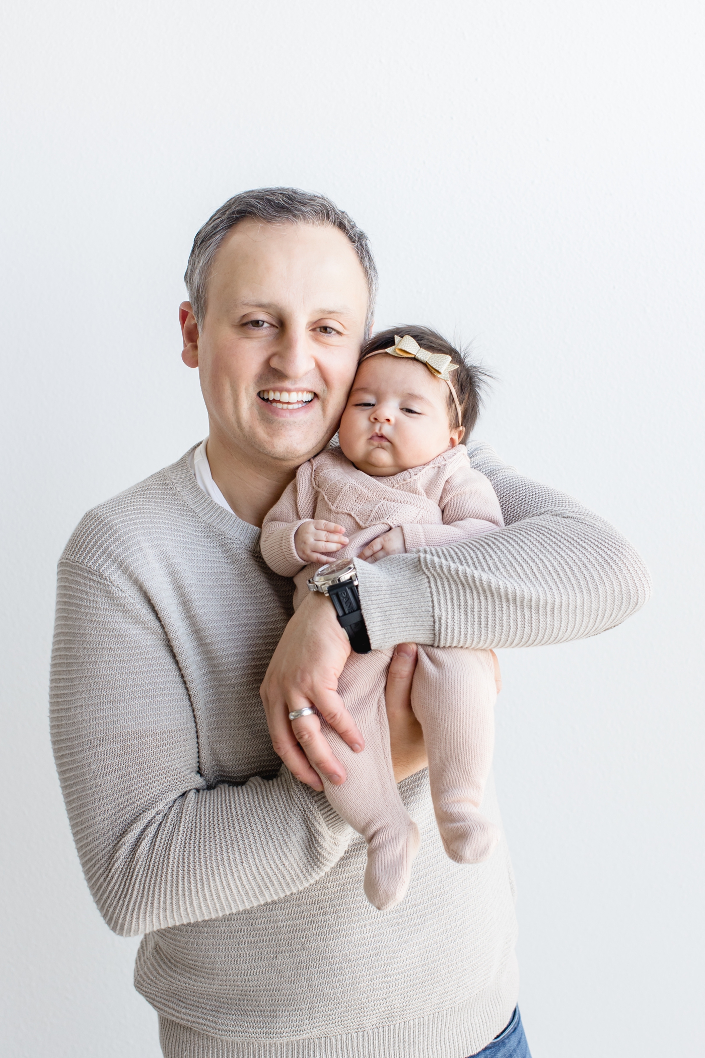 Dad holding baby and smiling during portrait session for three month milestone. Photo by Sana Ahmed Photography.