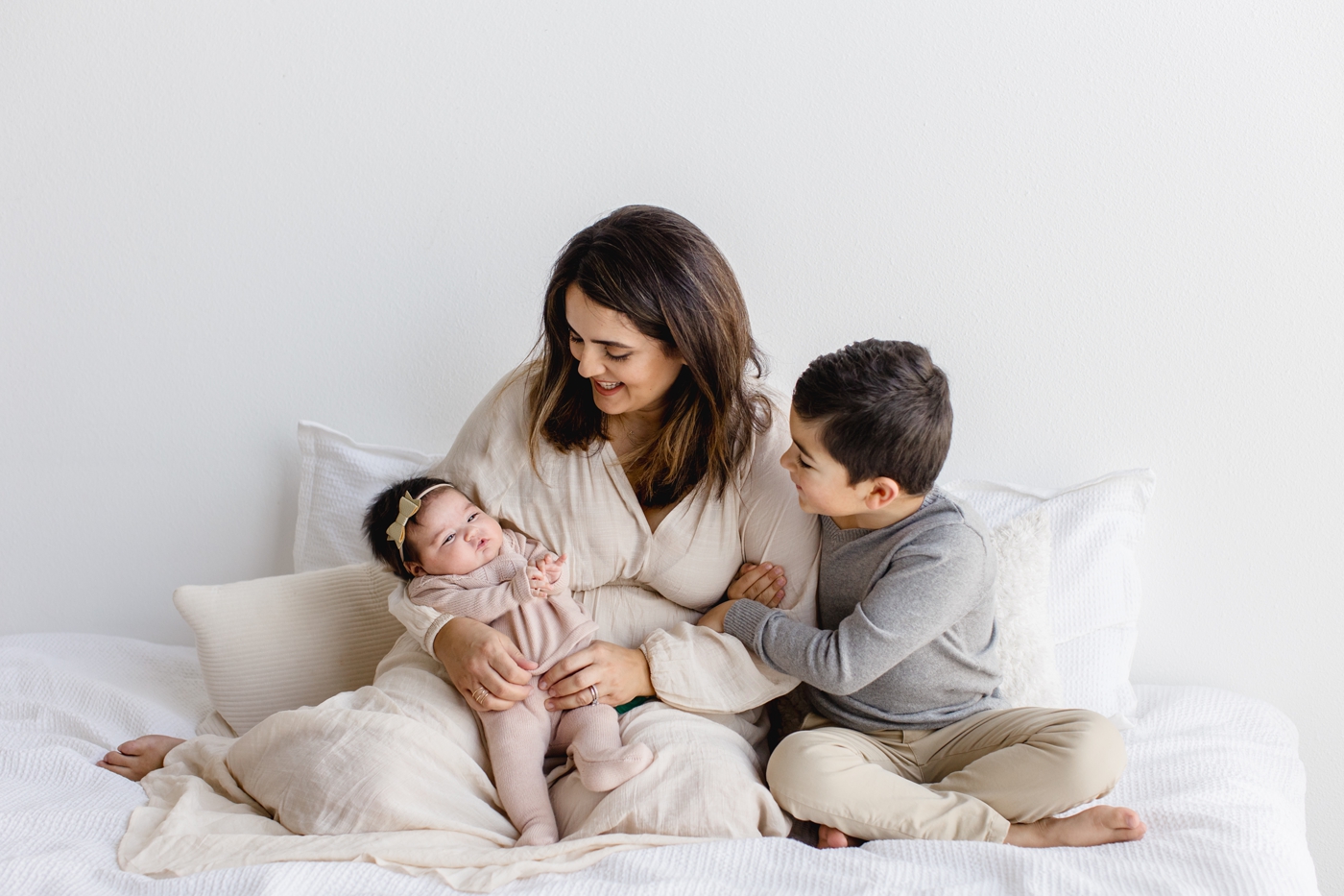 Mom with two children posting on bed during session with Austin photographer, Sana Ahmed Photography.