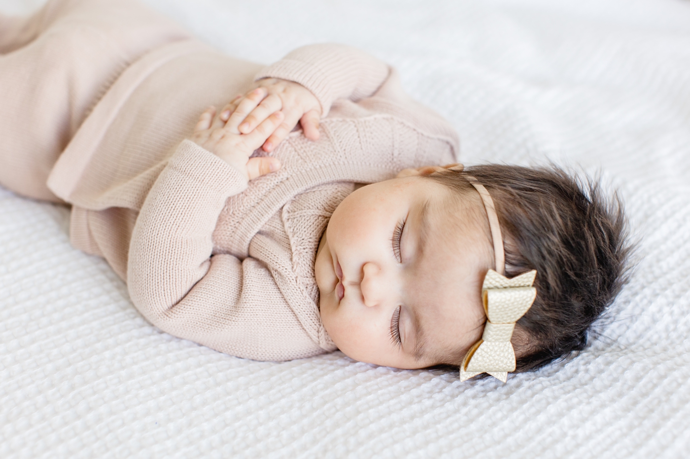 Baby sleeping with knit outfit and bow during photo session with Sana Ahmed Photography.