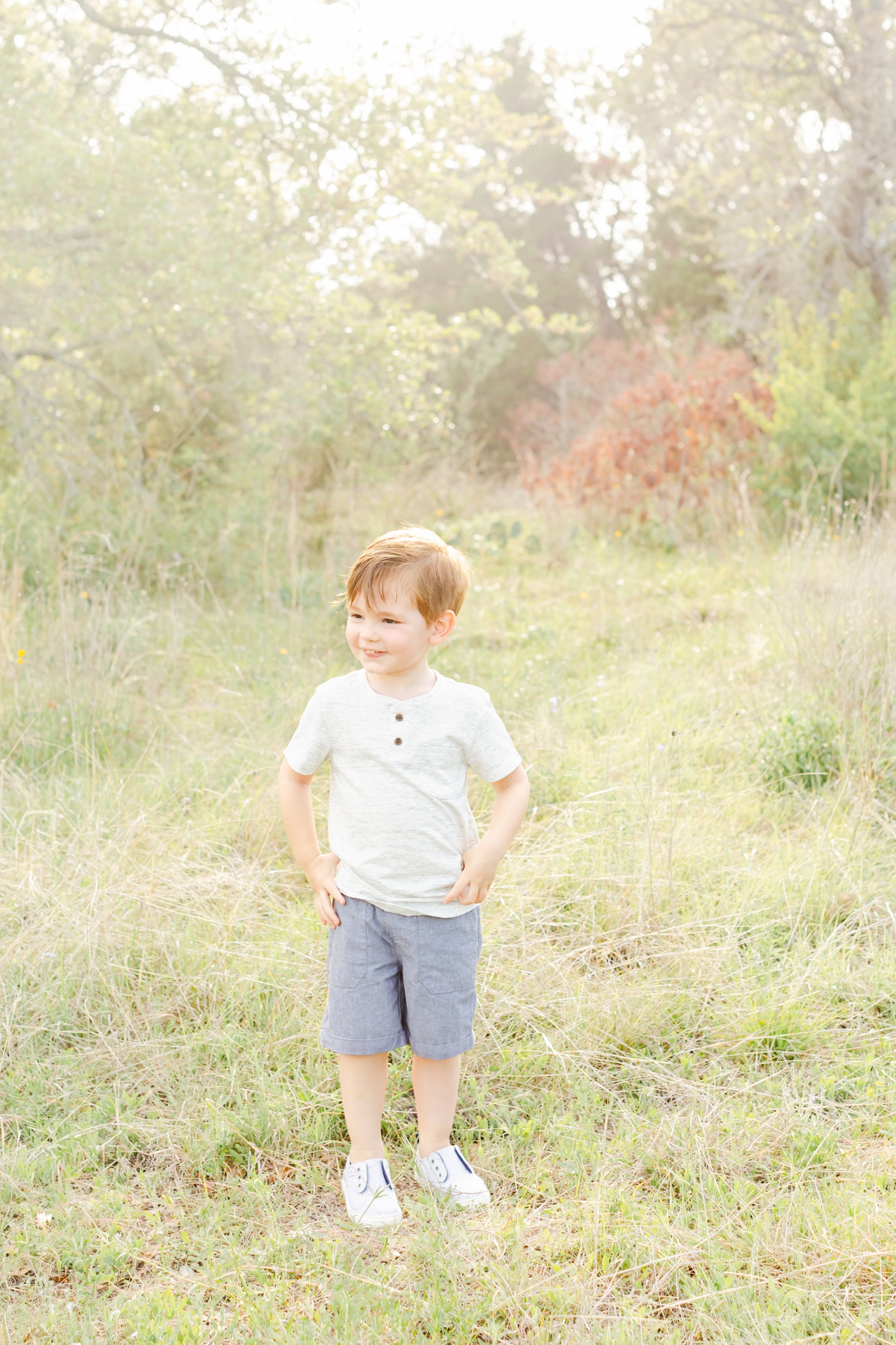 Little boy pulling his shirt down in a field family session. Photo by Sana Ahmed Photography.